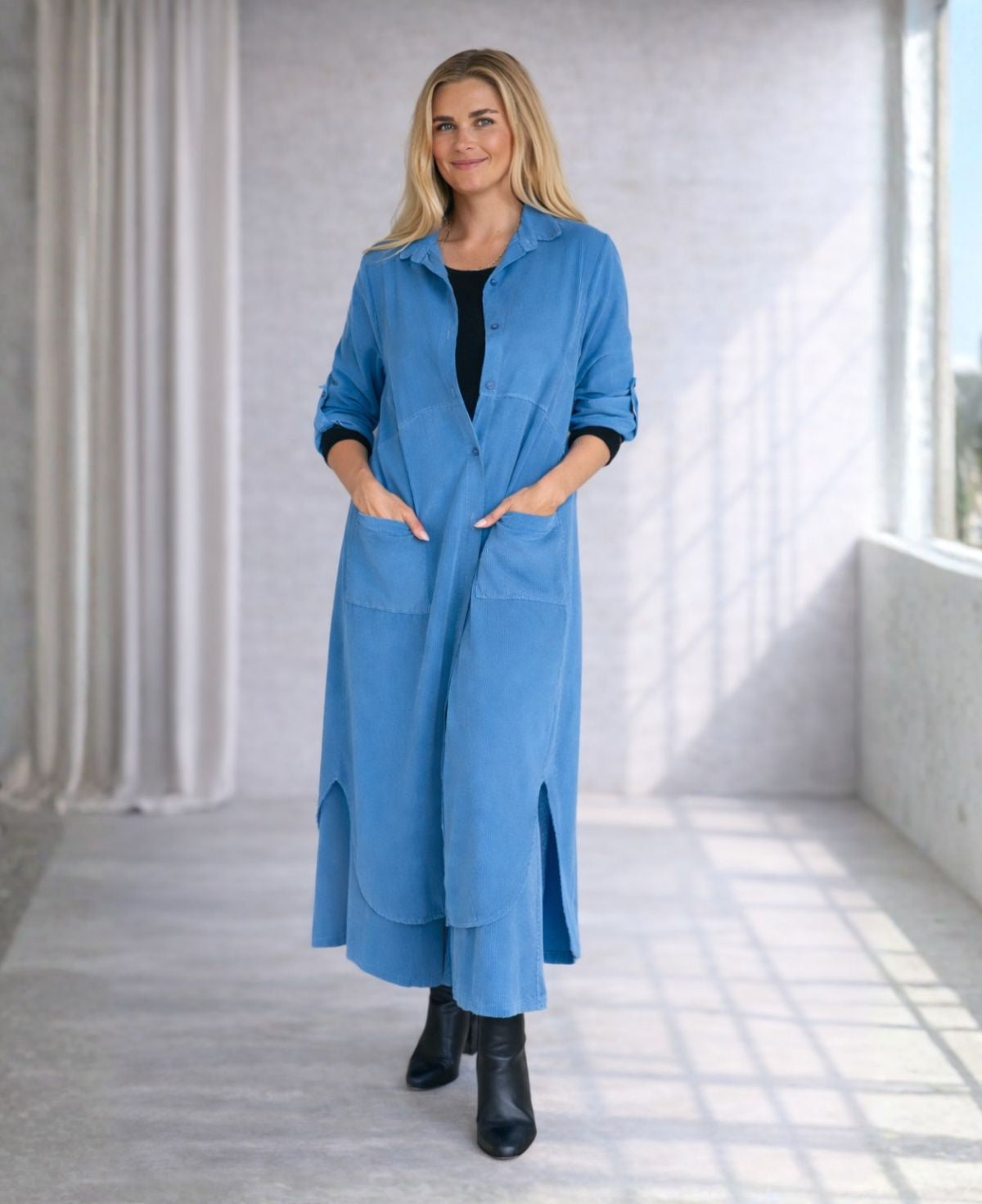 Model wearing the Empire Fray fine-rib corduroy dress in Blue Haven with matching wide-leg pants, photographed in soft natural studio light.