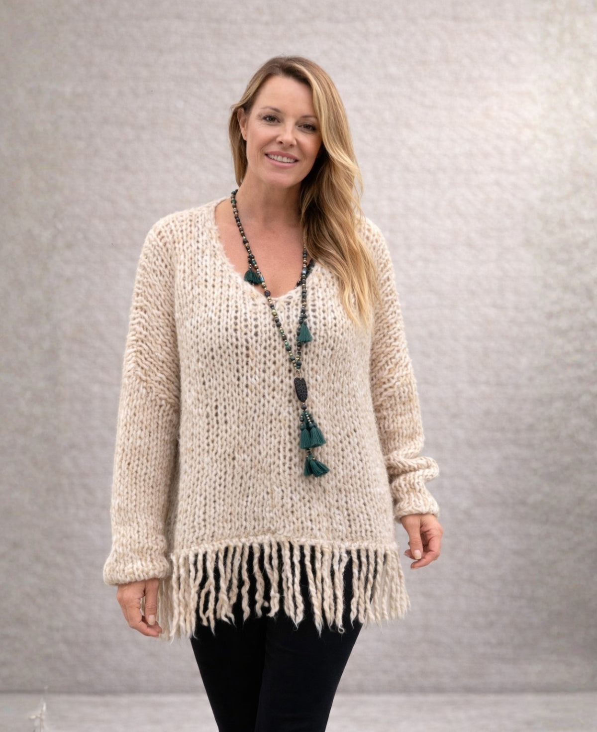 Model wearing beige mohair blend jumper with loose knit and fringe hem, styled simply in studio