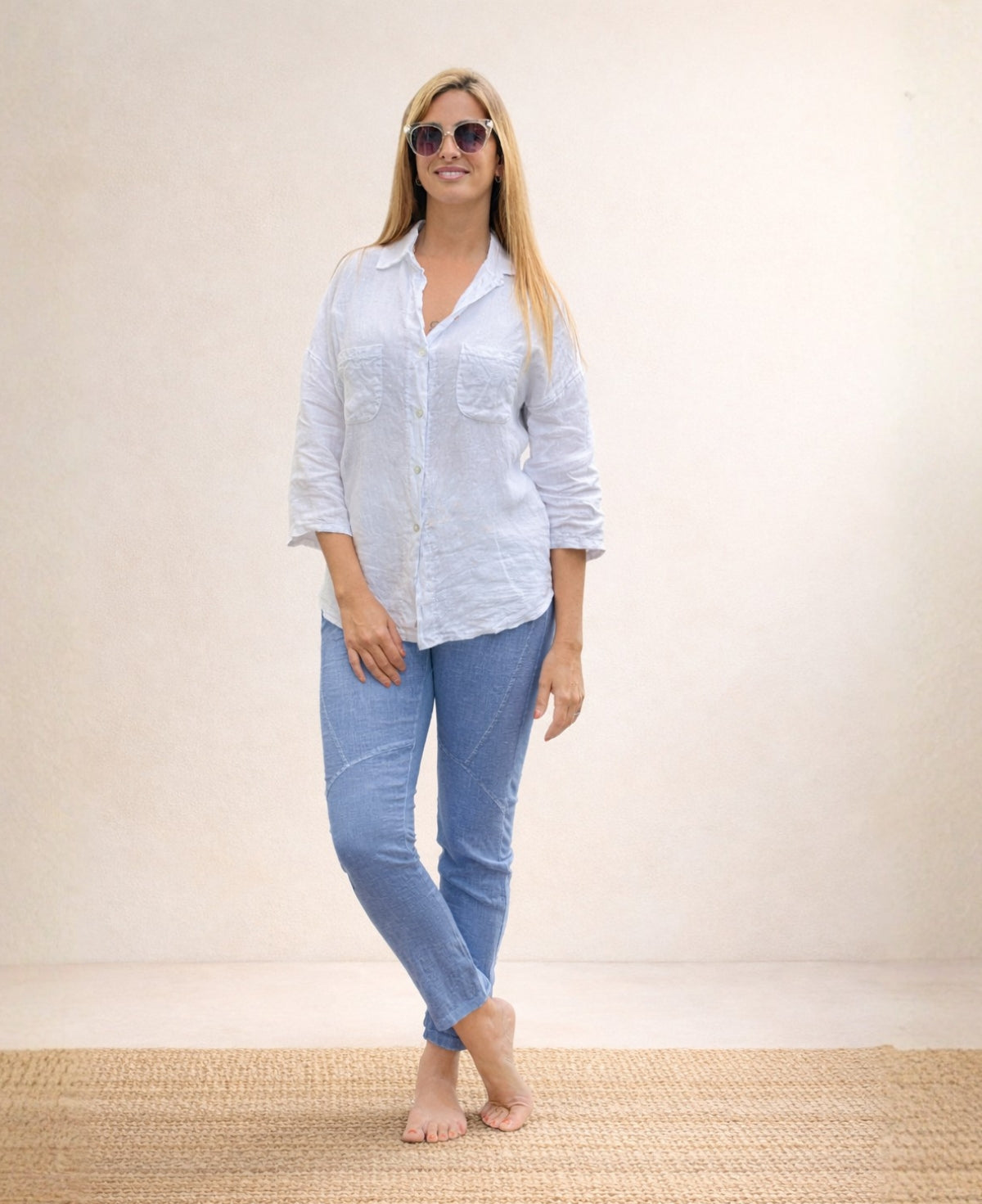 Full body front view of the Jordan Linen Pants in denim blue with legs crossed, showing linen texture and ribbed waistband.