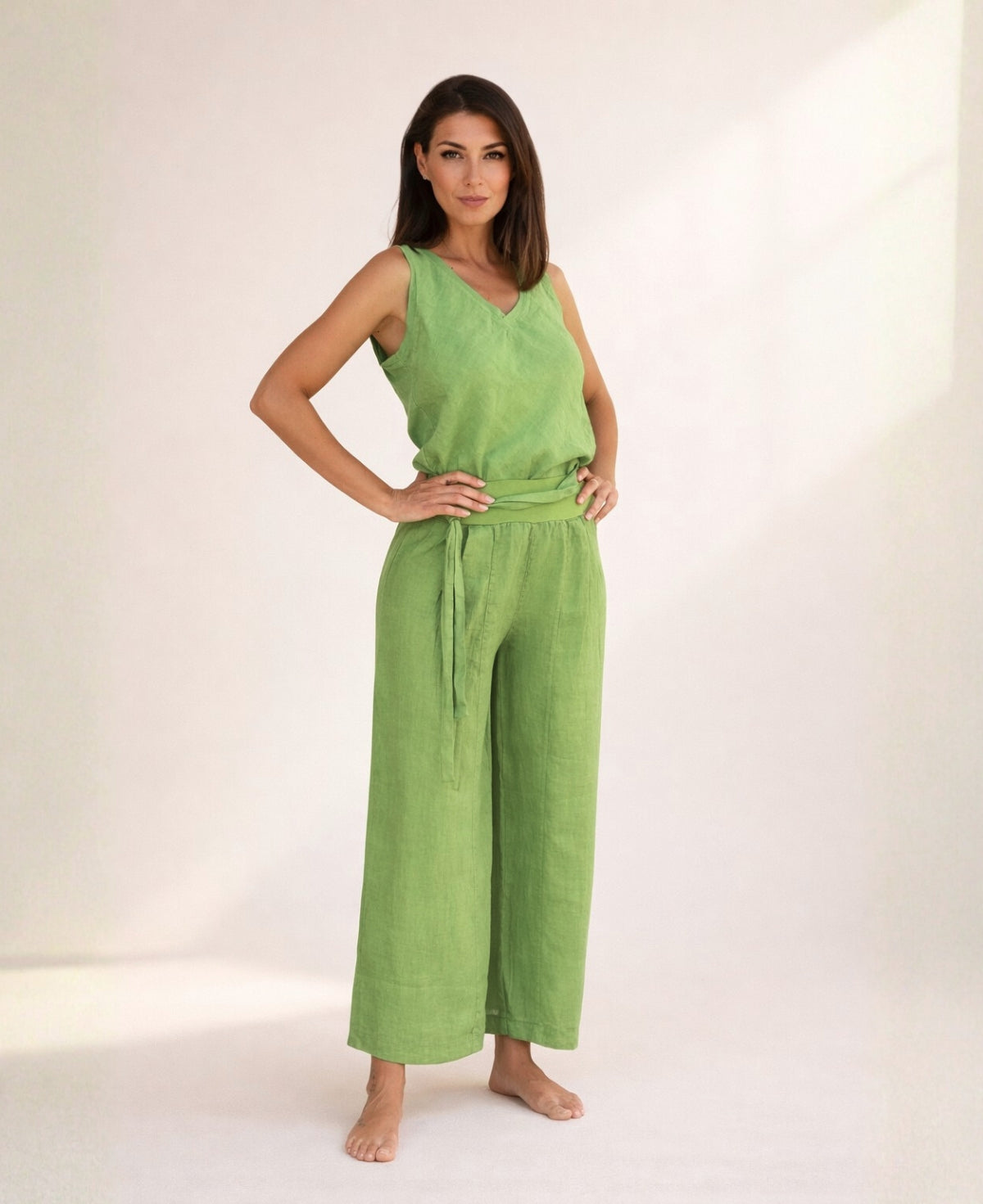 Woman wearing kiwi green linen palazzo pants with wide legs and stretch waist, front view showing lightweight linen fabric and relaxed fit.