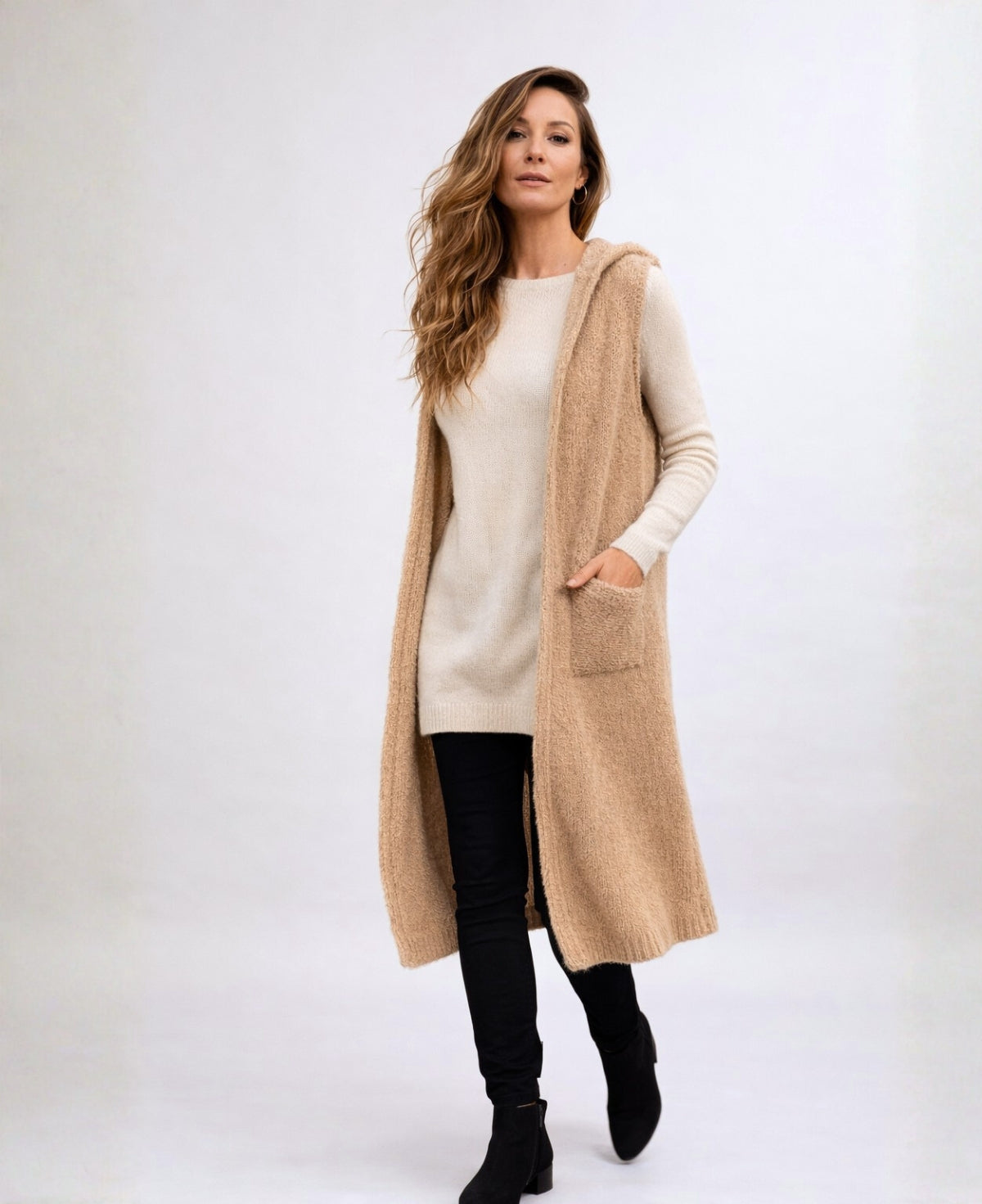 Front studio image of the Rockstar Long Vest in camel styled with the Le Coco Sweater in cream, black straight pants and black suede ankle boots against a warm off-white background.