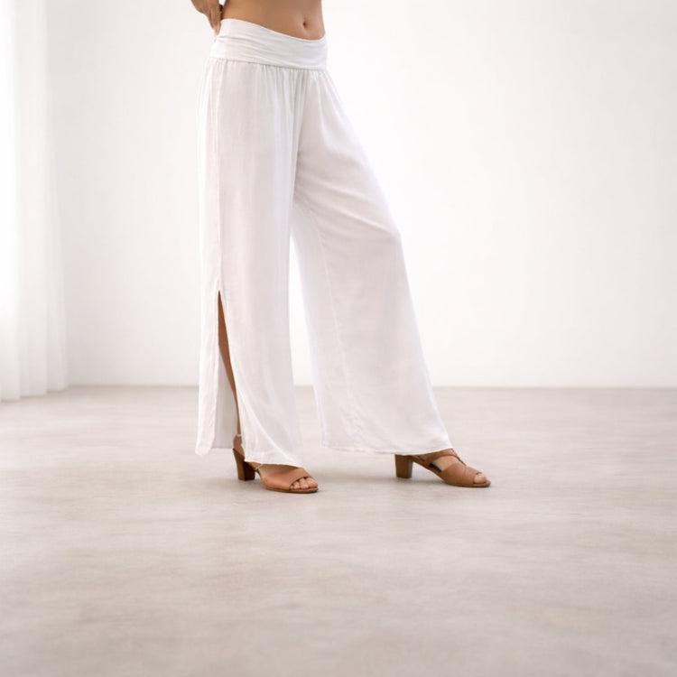 Women’s white silk wide leg pants with side slit detail in a minimalist studio setting