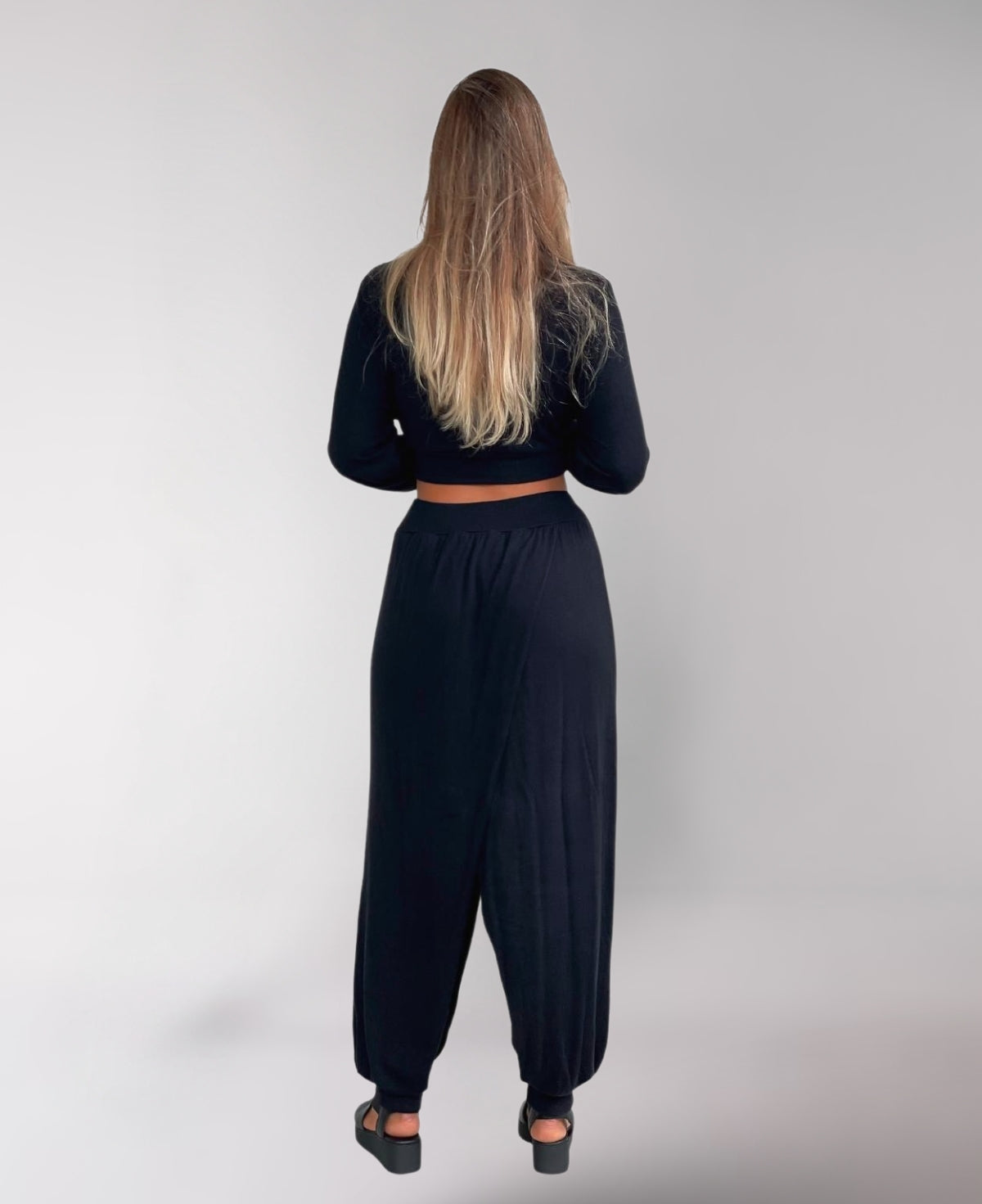 Back view of black Aladina Knit Harem Pants highlighting the streamlined silhouette and comfortable design, perfect for yoga and wellness sessions.