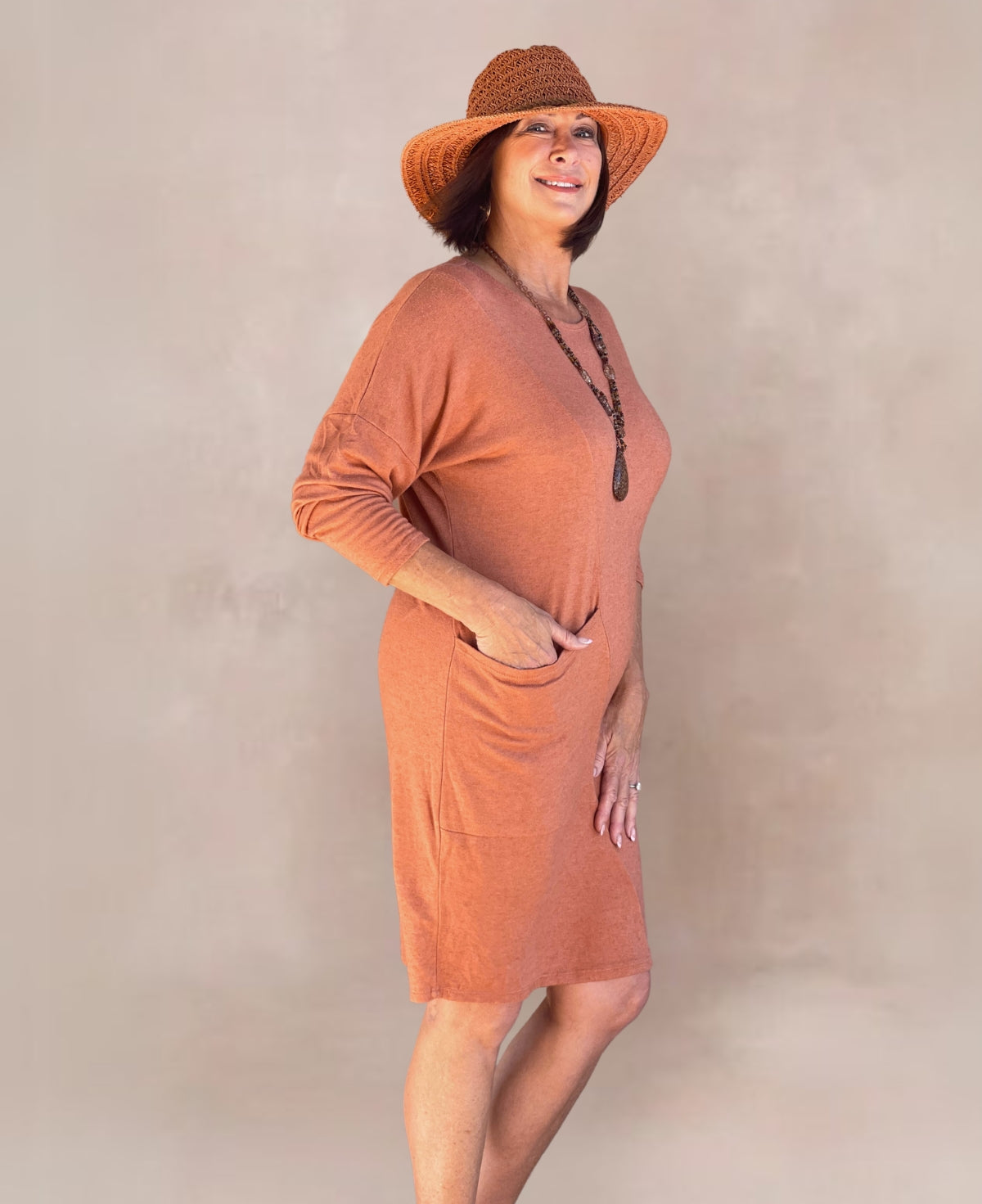 Warm copper knit dress in a cozy knee-length design, ideal for layering and everyday elegance.