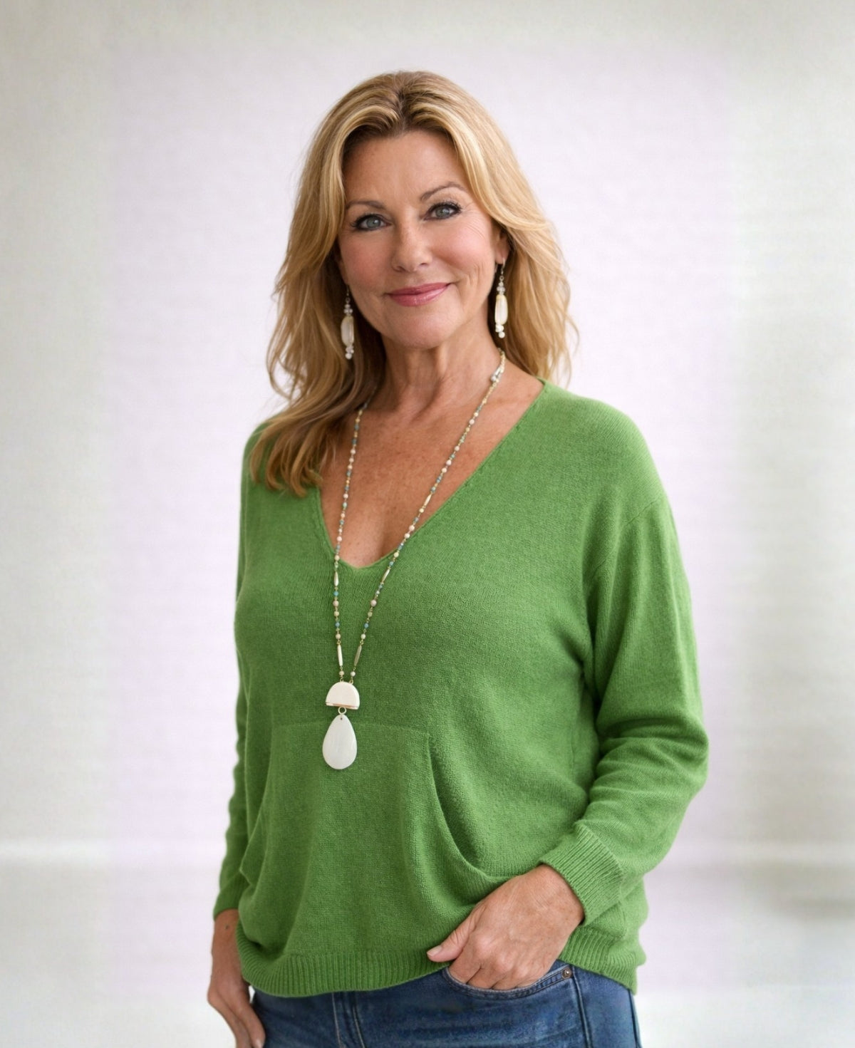 Model wearing apple green cashmere V-neck sweater in studio front view