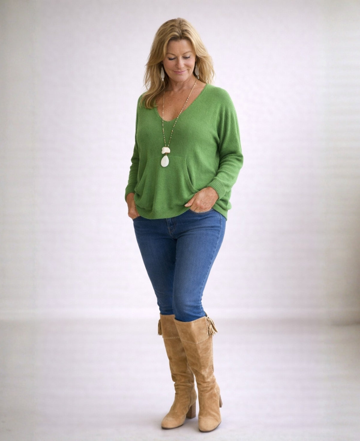 Full body view of apple green cashmere V-neck sweater styled in neutral studio