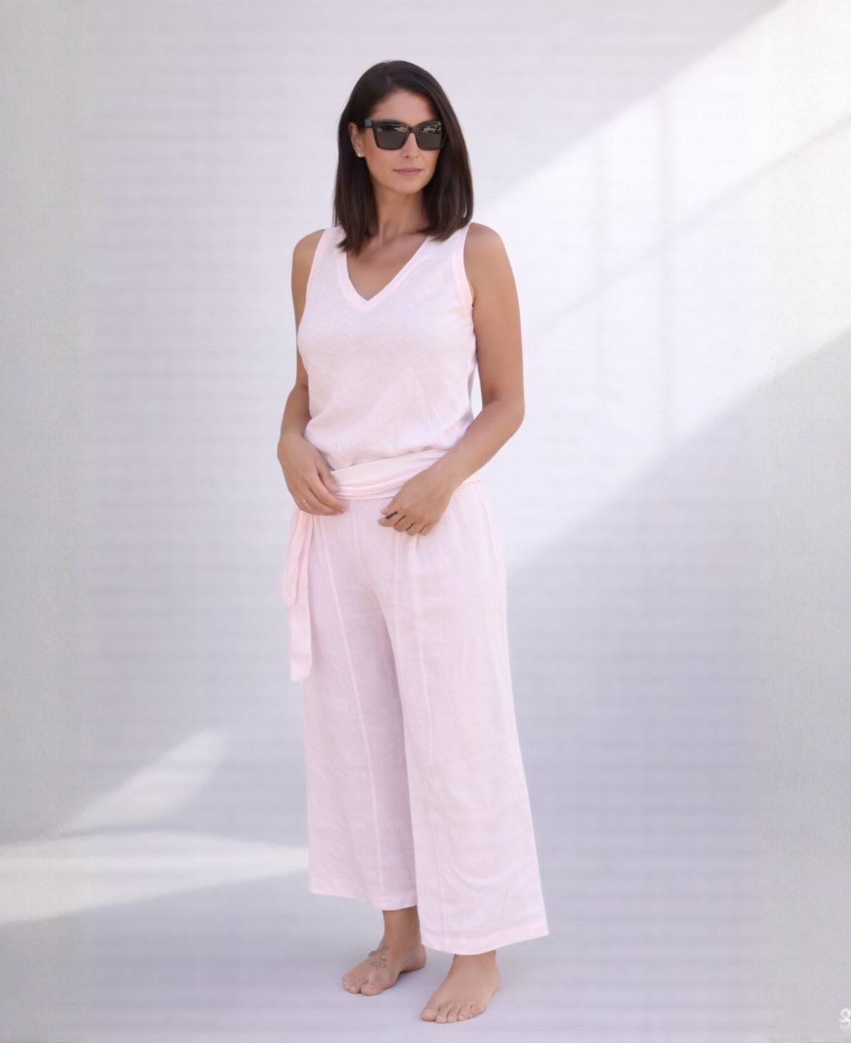 Woman wearing blush pink linen palazzo pants with wide legs and stretch waist, front view showing soft colour and breathable fabric.