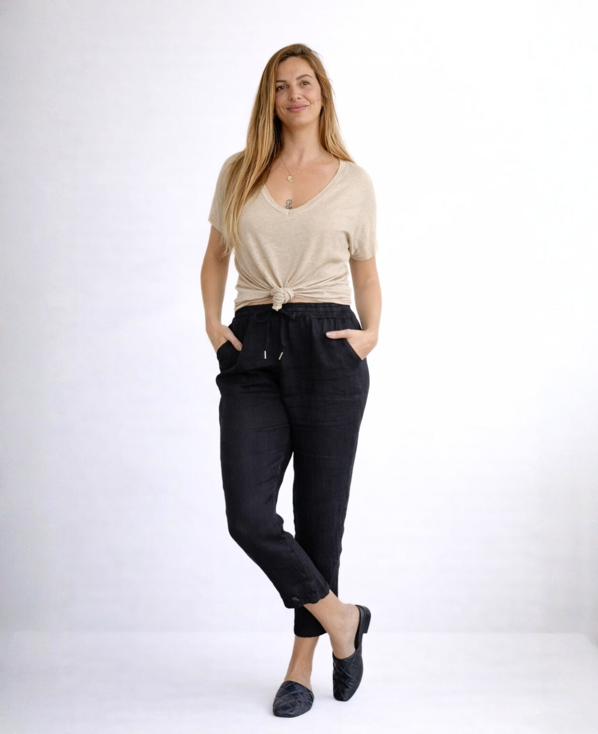 Black Brooklyn linen pants shown in full body front view with relaxed crossed stance, breathable linen fabric and tapered leg, studio photography