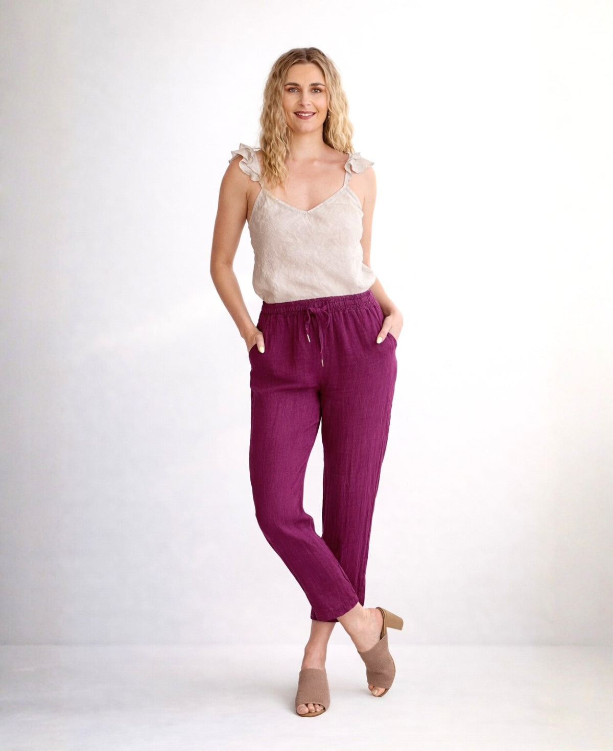 Sangria Brooklyn linen pants shown on model in full body front view with crossed legs, lightweight linen fabric and drawstring waist, studio background