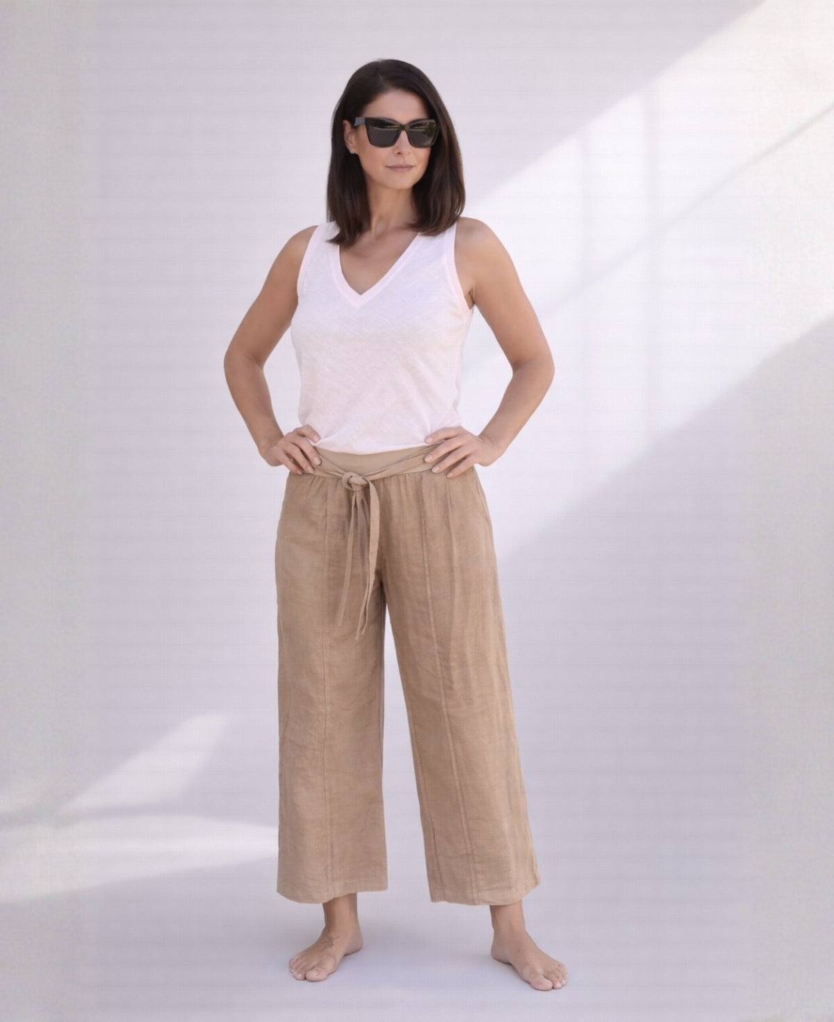 Woman wearing camel linen palazzo pants with wide legs and stretch waist, front view showing warm neutral tone and lightweight linen.