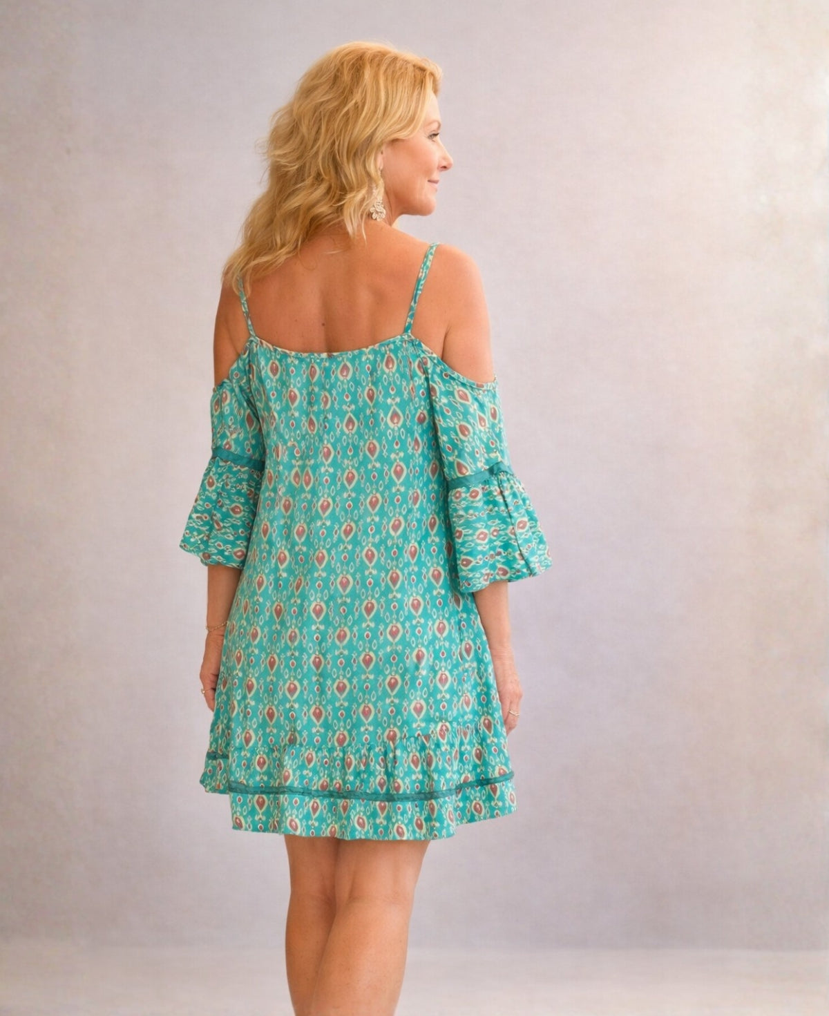 Back angled view of the Camellia silk dress in teal, showing the loose drape, thin shoulder straps and lightweight Indian silk fabric in a minimalist studio background.
