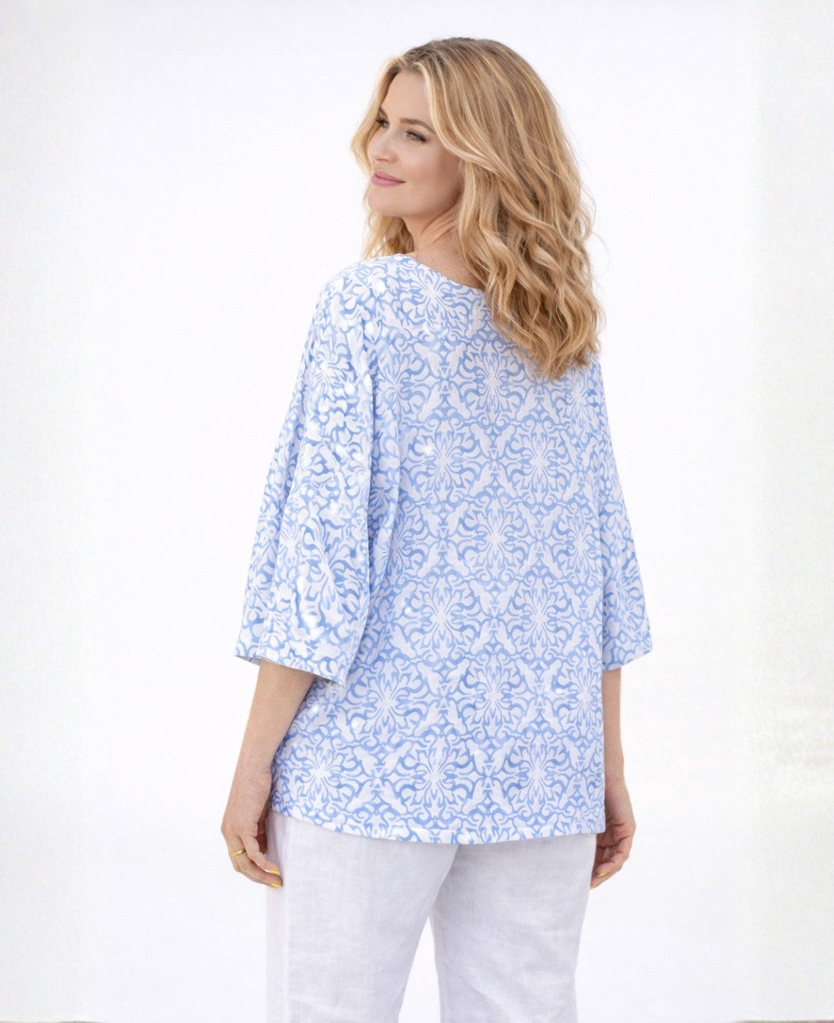 Back view of Capri Linen T-shirt in sky blue showing straight hem and relaxed fit, worn by blonde model in a studio setting