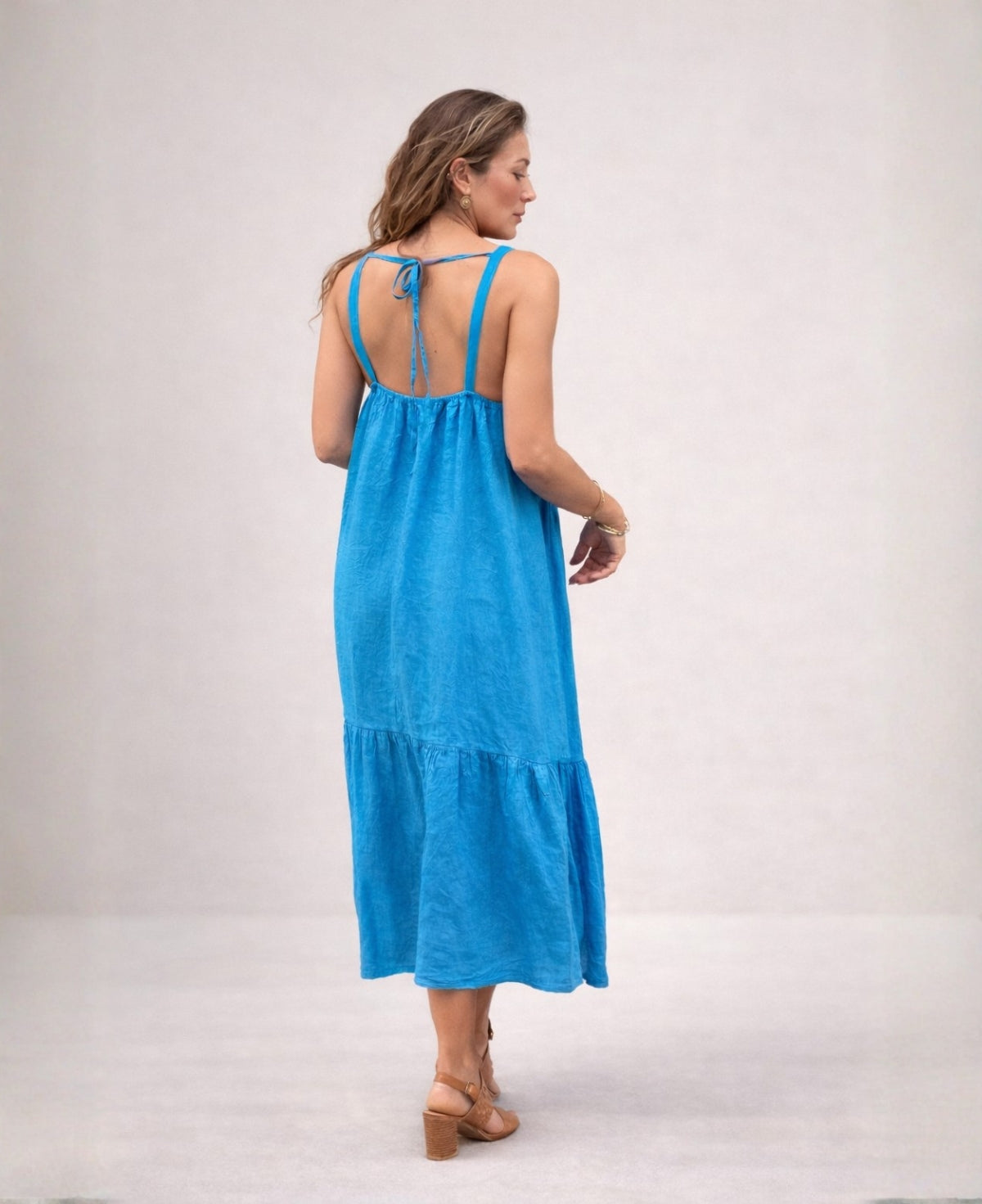 Back view of the Cassey linen dress in turquoise, highlighting shoulder straps and tie-back detail.