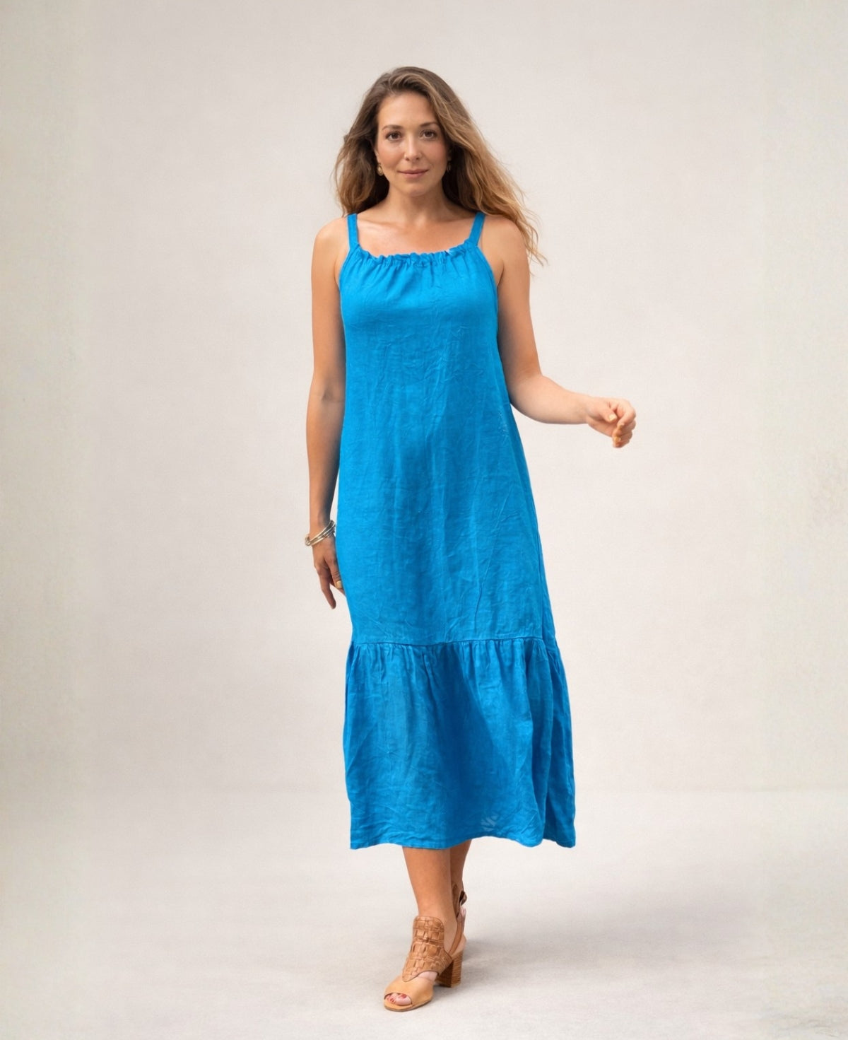 Model wearing the Cassey linen dress in turquoise, front view, showing relaxed fit, gathered neckline and tiered midi length.