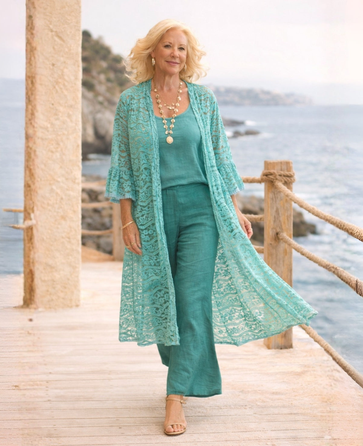 Editorial image of the Daniella Lace Kimono in Tiffany styled with linen separates on a coastal boardwalk, capturing relaxed Australian resort elegance.