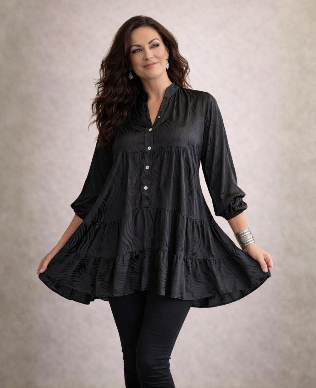 Black Eden Pattern satin top mini dress with embossed texture, styled on a brunette model against a soft shadowed greige background.