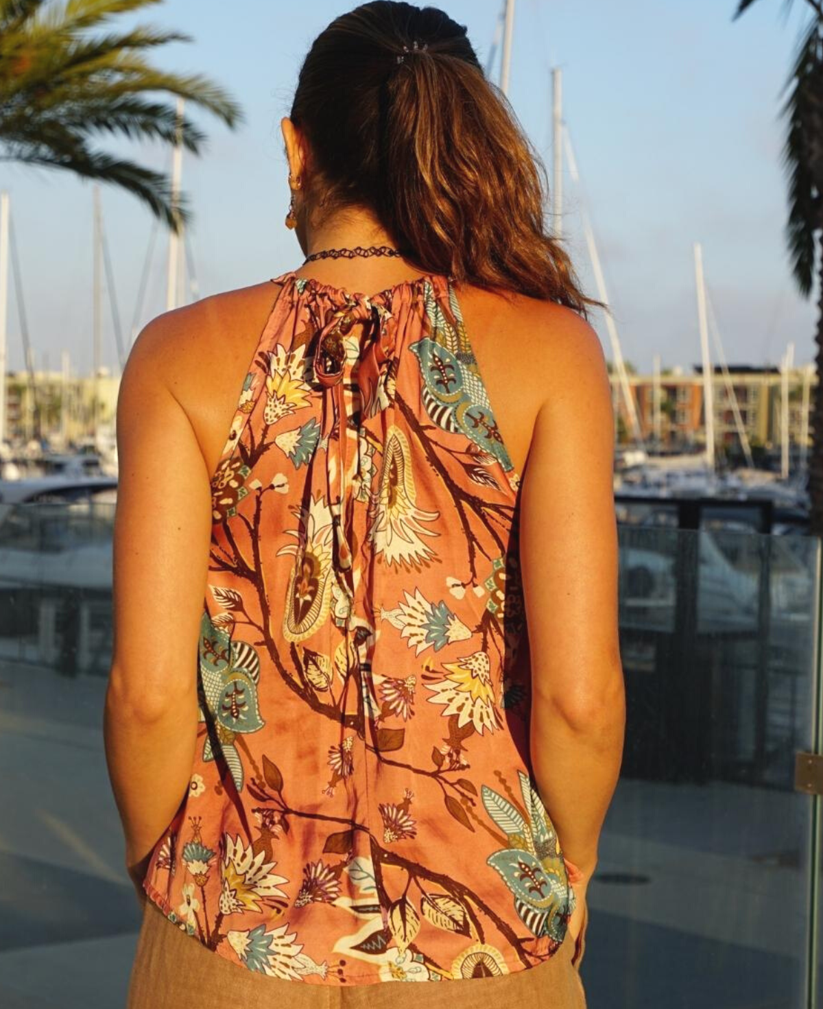 Gardenia halter top in rose gold with a delicate floral print, featuring a flattering low back and tie-up neckline. A chic and versatile summer statement piece.