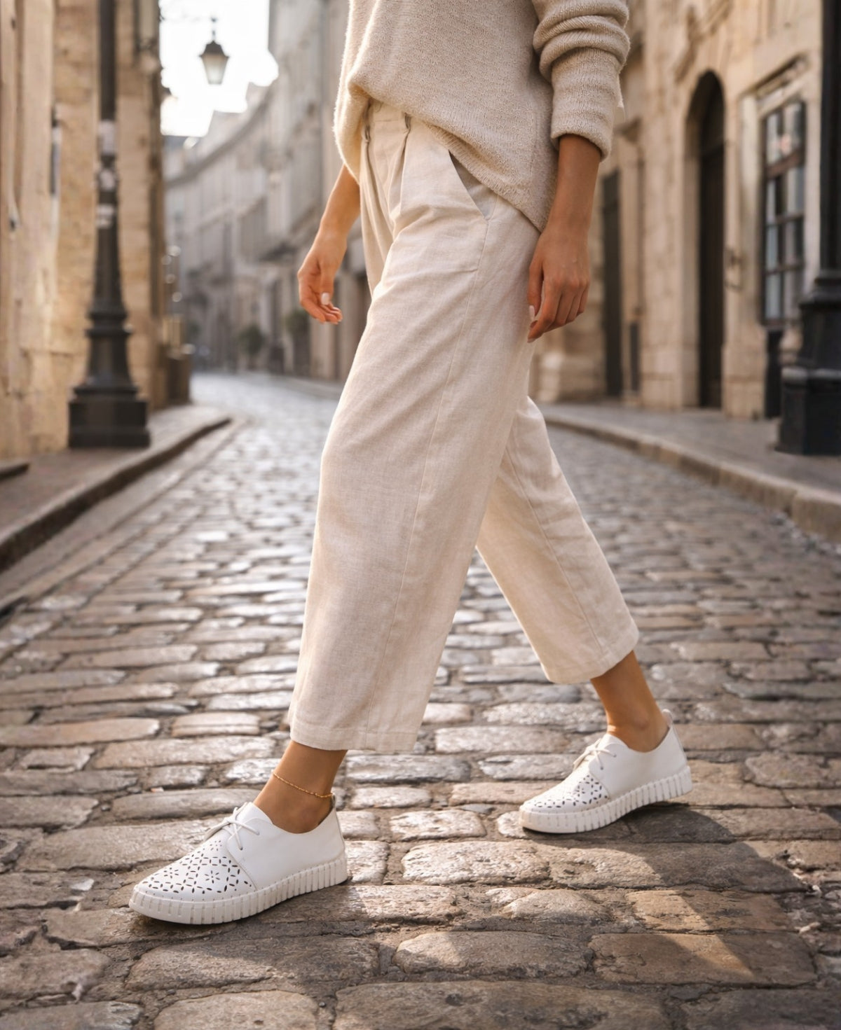 Woman wearing Hexter white leather sneakers styled with neutral tones on a city street, showcasing an effortless urban look