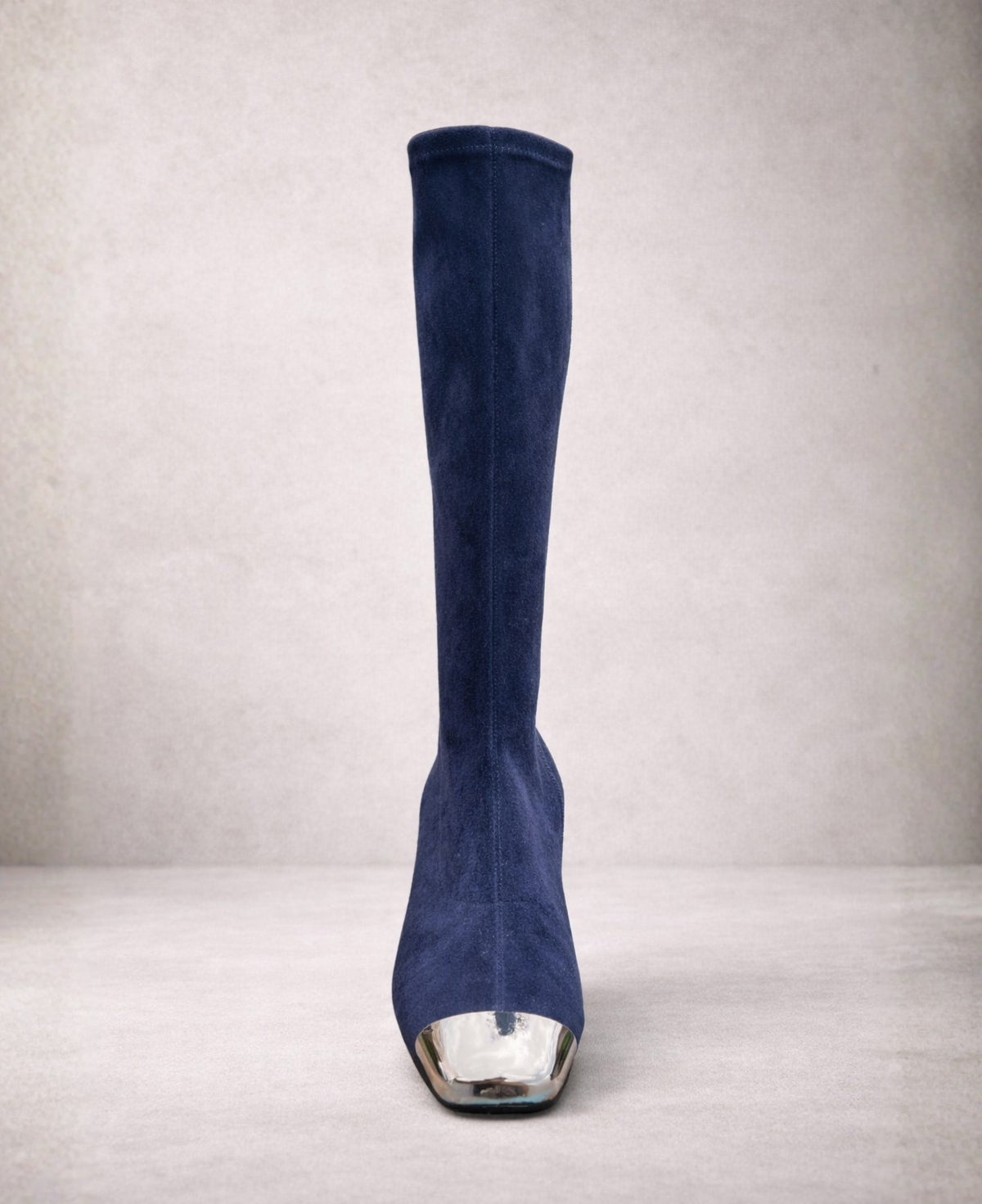 Front view of Hoppey navy suede knee high boots highlighting the sleek silhouette and metallic silver toe cap against a modern neutral background.