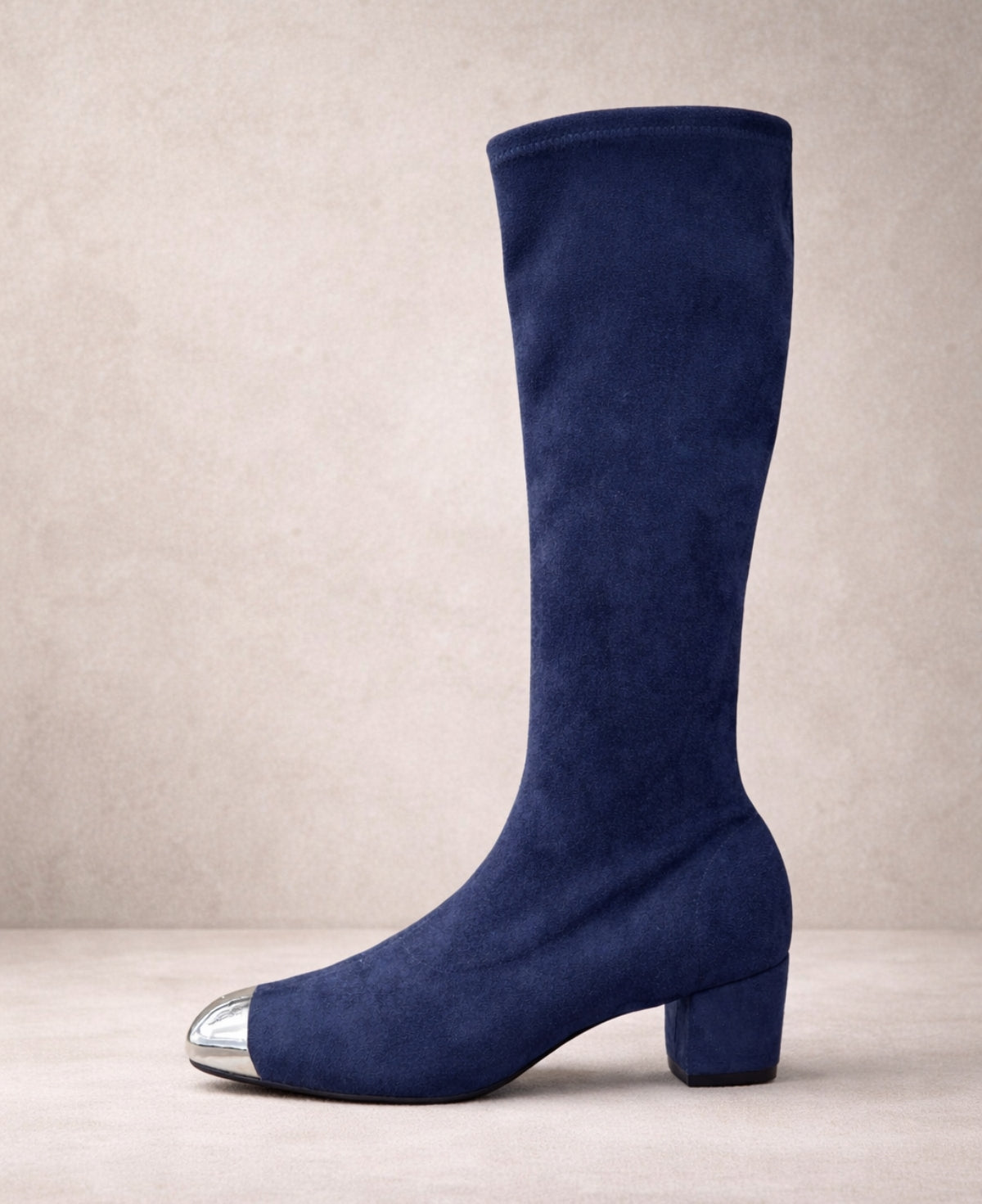 Side view of Hoppey navy suede knee high boots featuring a block heel and polished silver toe cap on a minimalist neutral background.