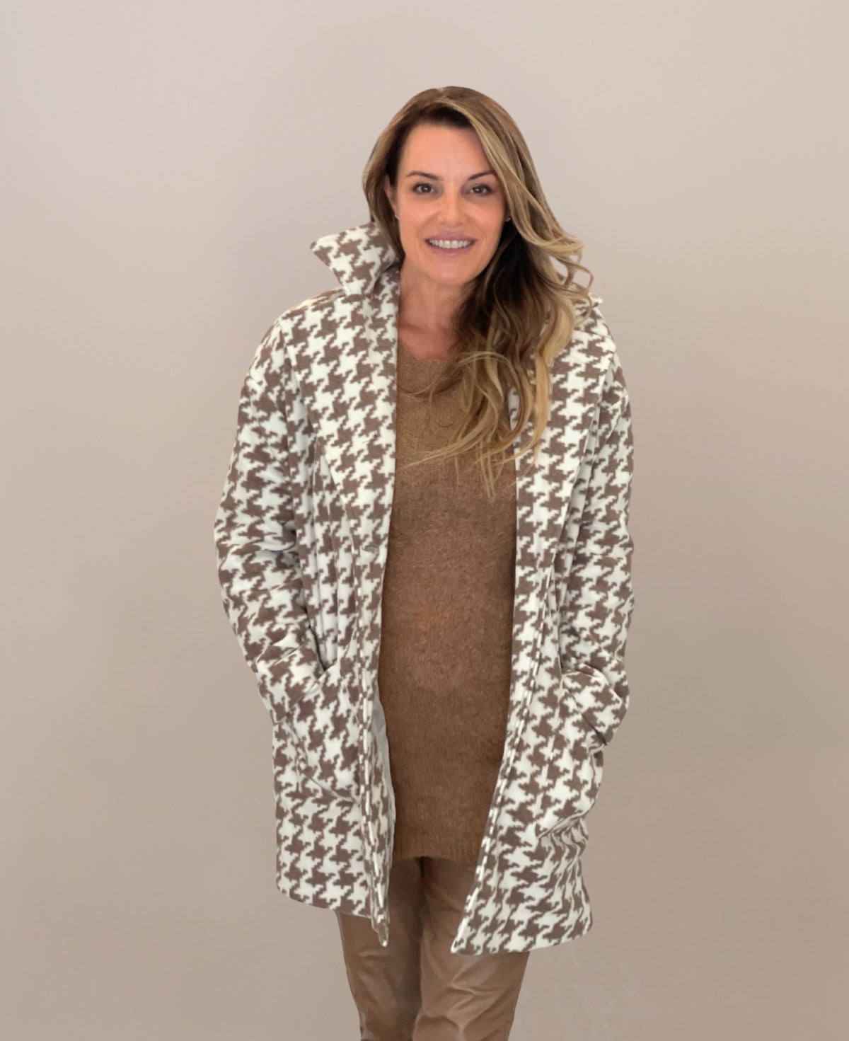 Cream mid-length houndstooth-patterned coat featuring a timeless design, fully lined for extra warmth, perfect for elevating any outfit with its refined and versatile style.