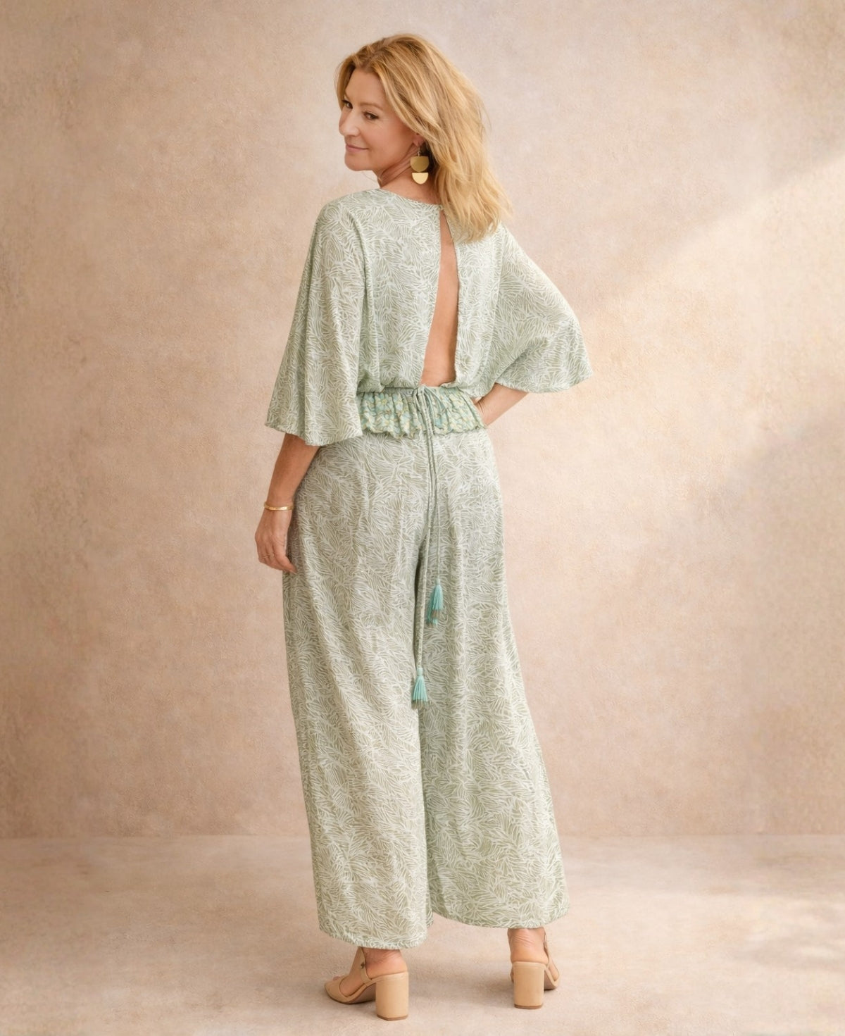 Angled back view of the Iris Silk Set in sage green Indian silk blend featuring open back top with tie detail, wide leg pants and tassel waistband.