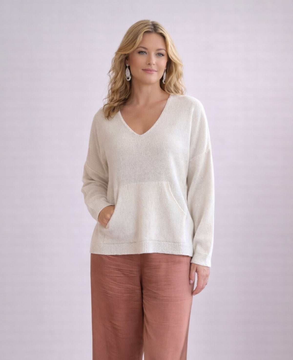 Front view of ivory cashmere V-neck sweater styled with satin pants in studio