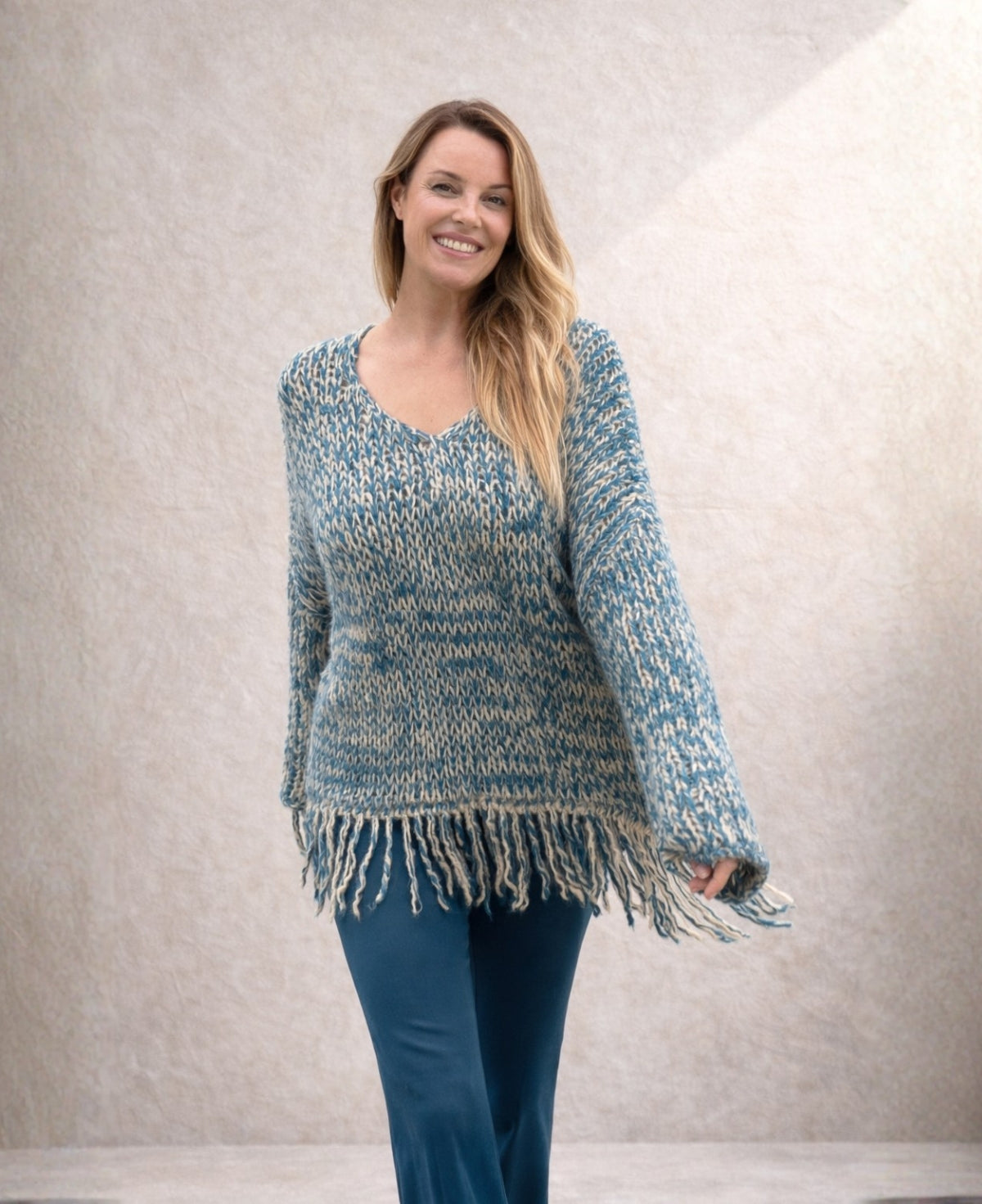 Model wearing blue mohair blend jumper with V neckline and fringe hem, styled with jeans in studio background
