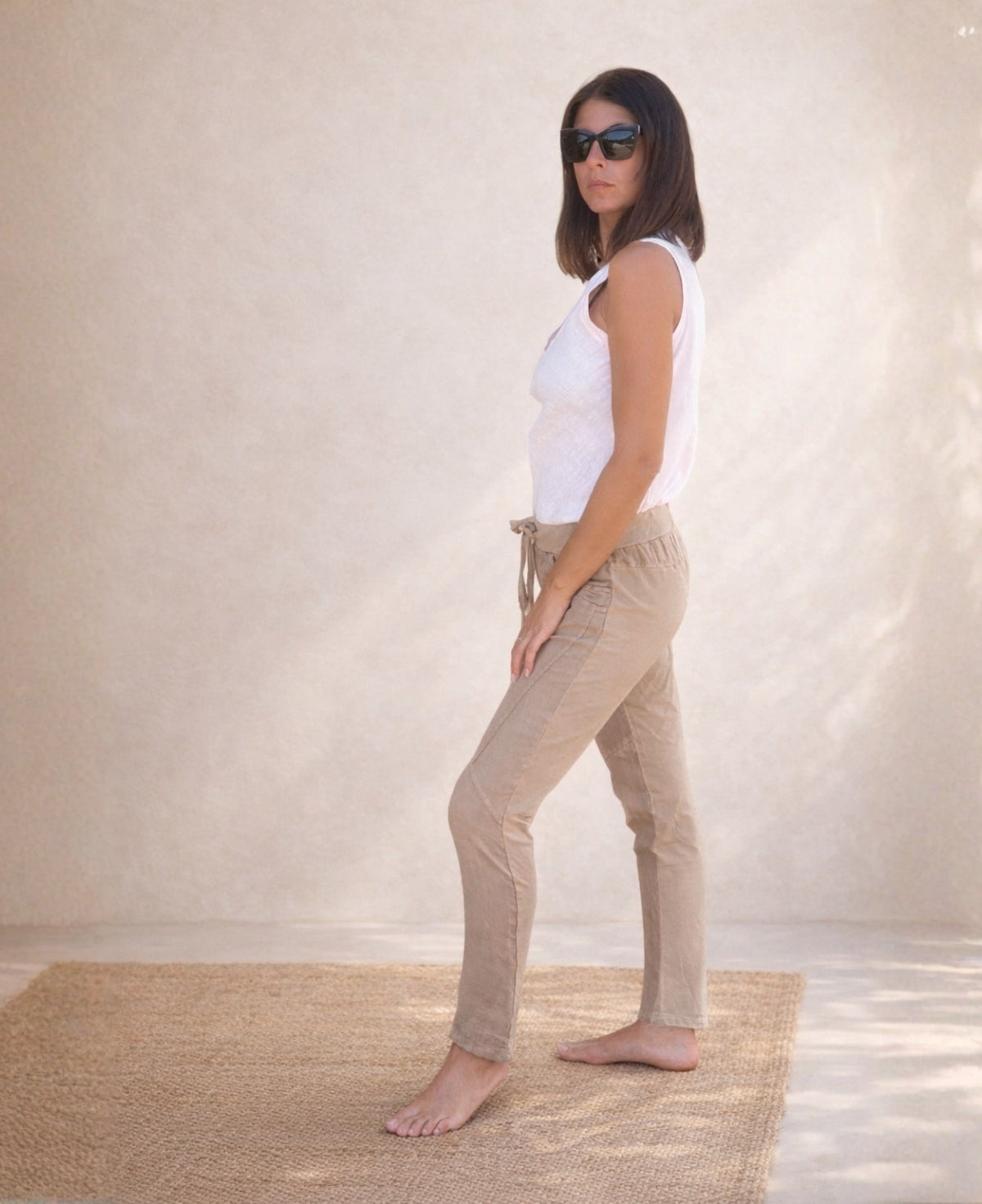 Full body side view of the Jordan Linen Pants in camel featuring narrow leg cut, front seam detail and ribbed stretch waistband.