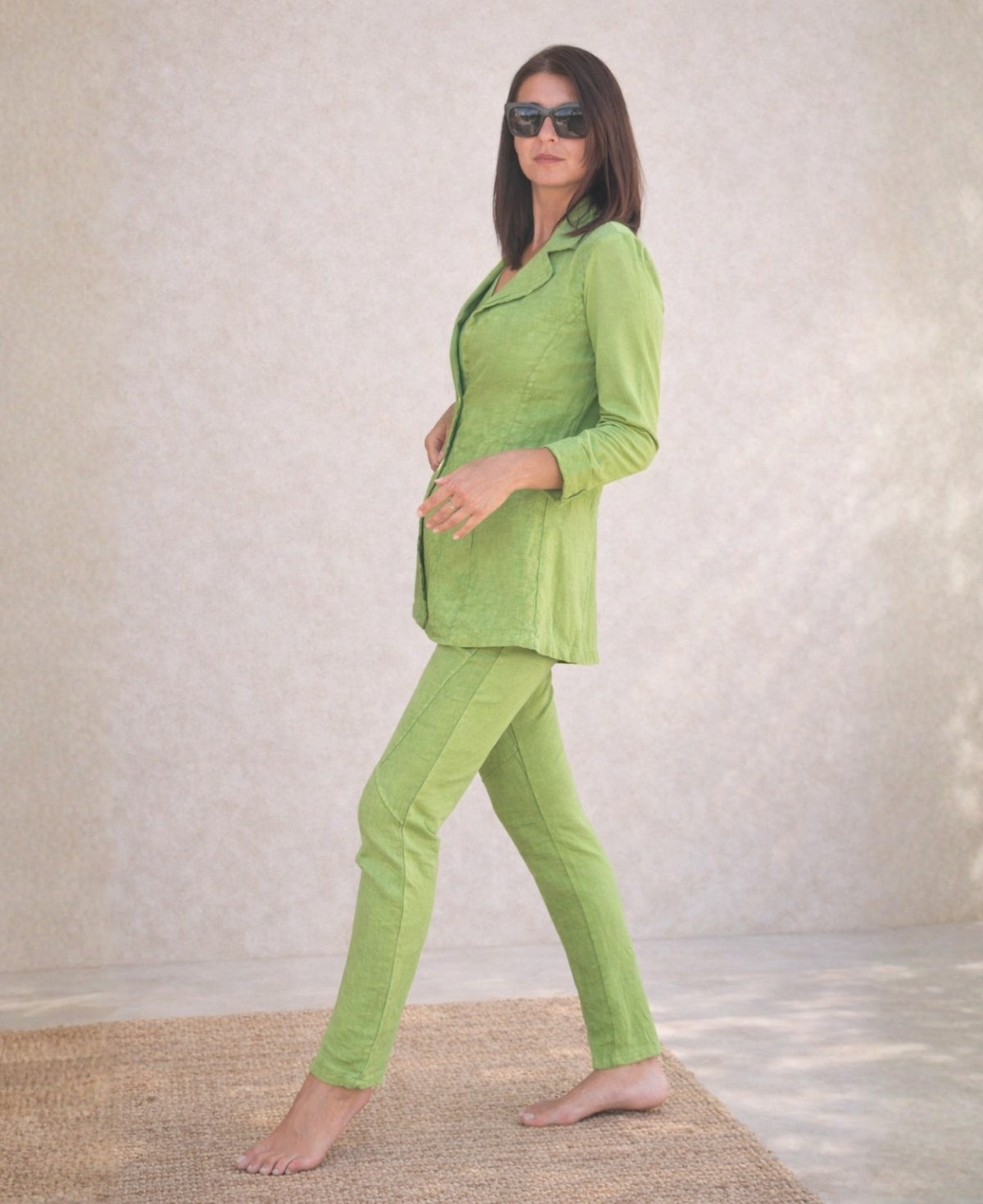 Full body side view of the Jordan Linen Pants in kiwi styled with matching blazer, front foot forward showing seam detail.