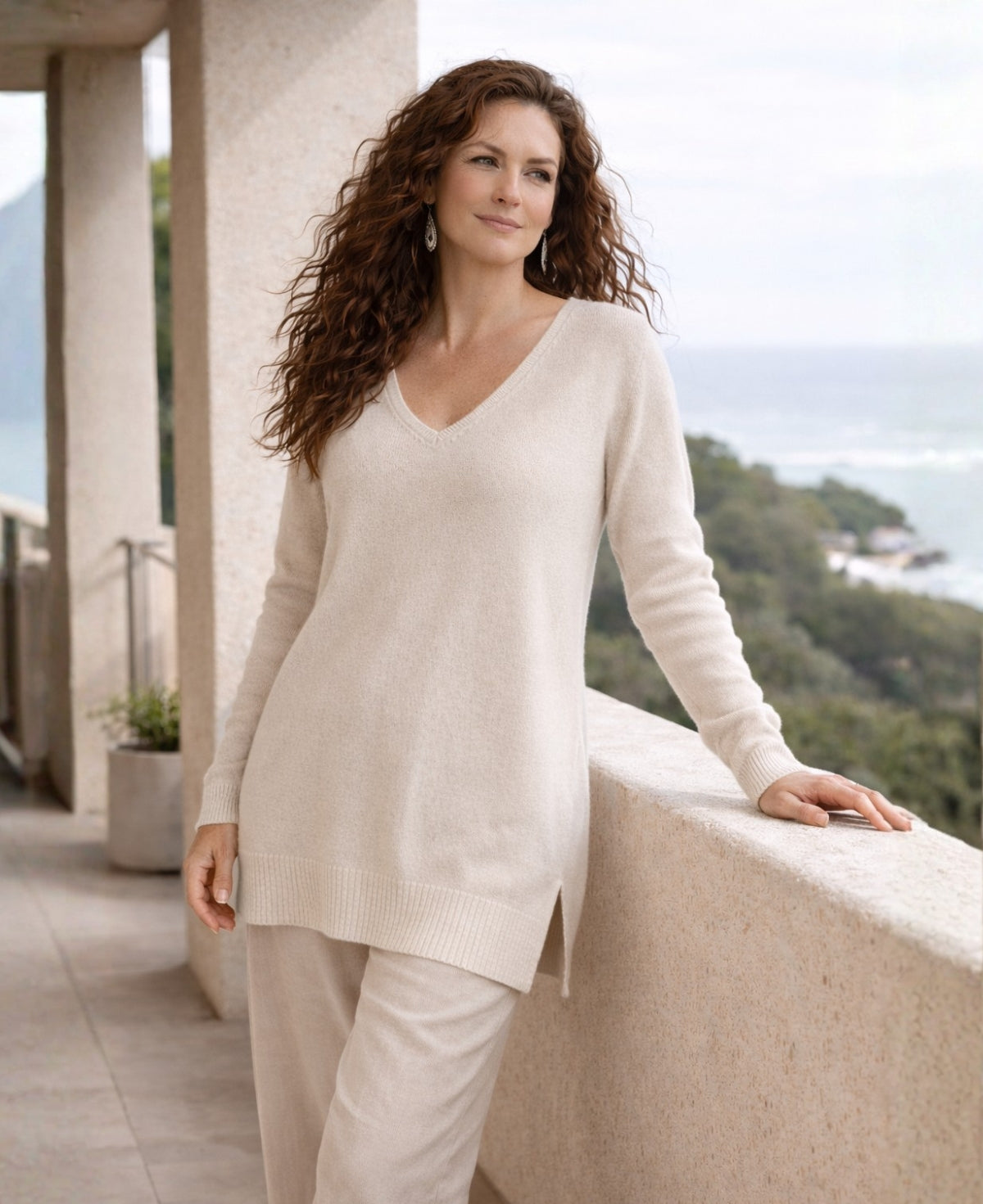 Model wearing ivory Kallista cashmere blend long sweater on a coastal balcony in soft Australian winter light