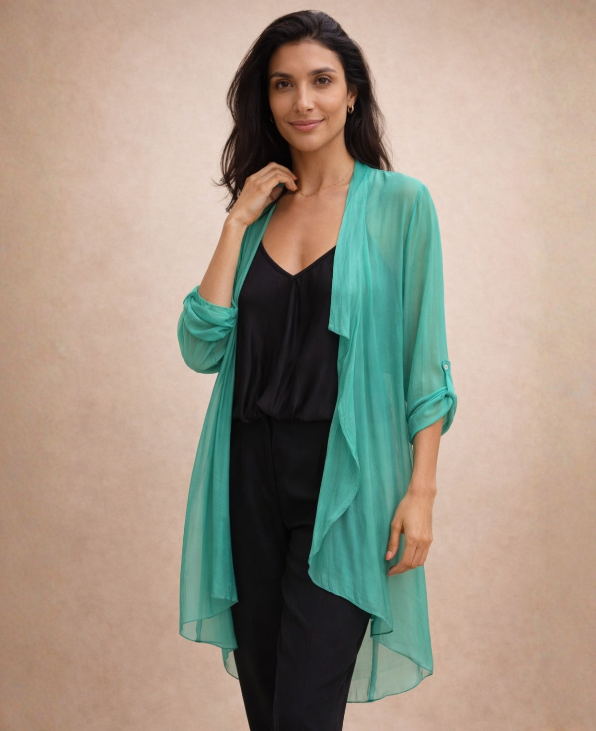 Close view of the Katherine Sheer Silk Overlay in emerald green showing the waterfall front, roll-tab sleeves and sheer silk texture over a black camisole.