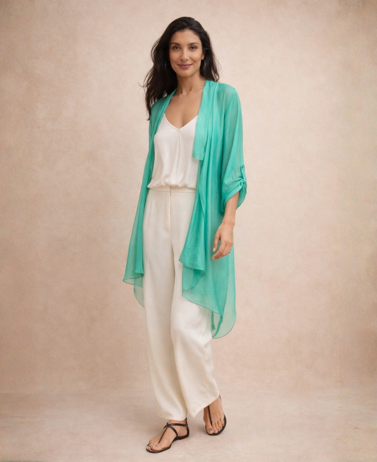 Emerald green Katherine Sheer Silk Overlay layered over an ivory camisole and ivory trousers, shown in a soft studio setting highlighting the lightweight translucent silk fabric.