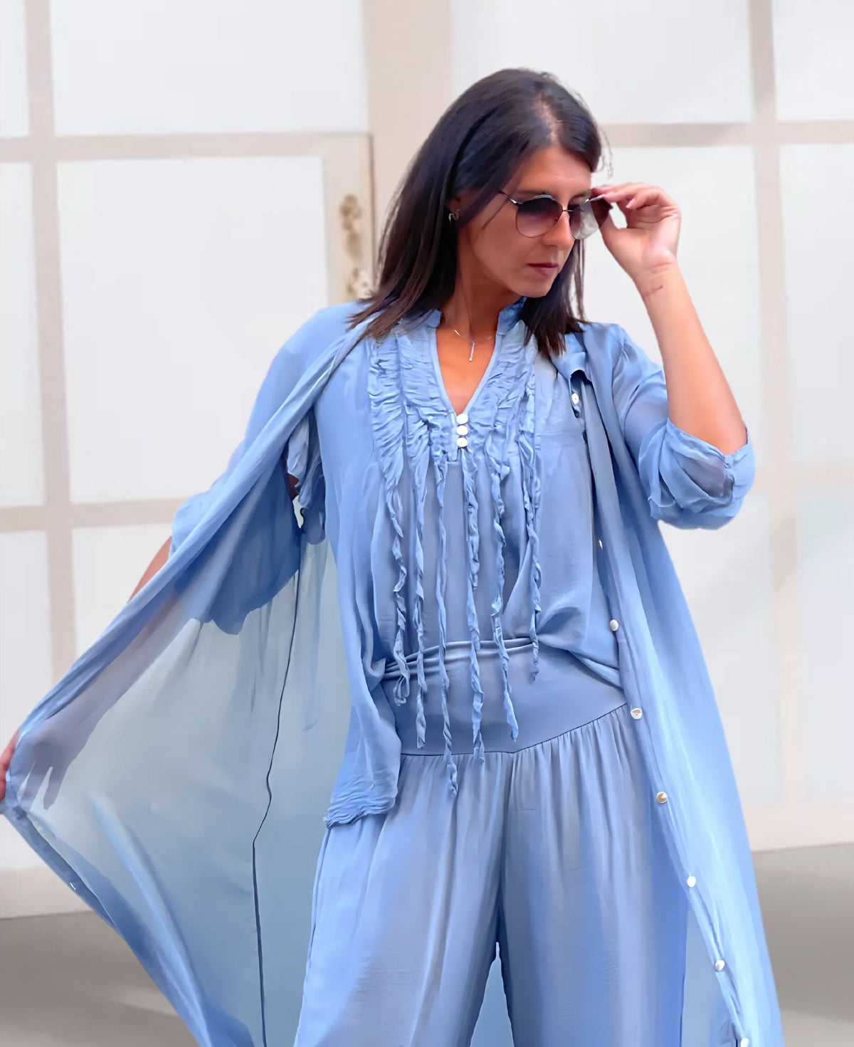 Elegant silk summer top with sheer cap sleeves, delicate button accents, and ruffle details in a timeless, feminine design.