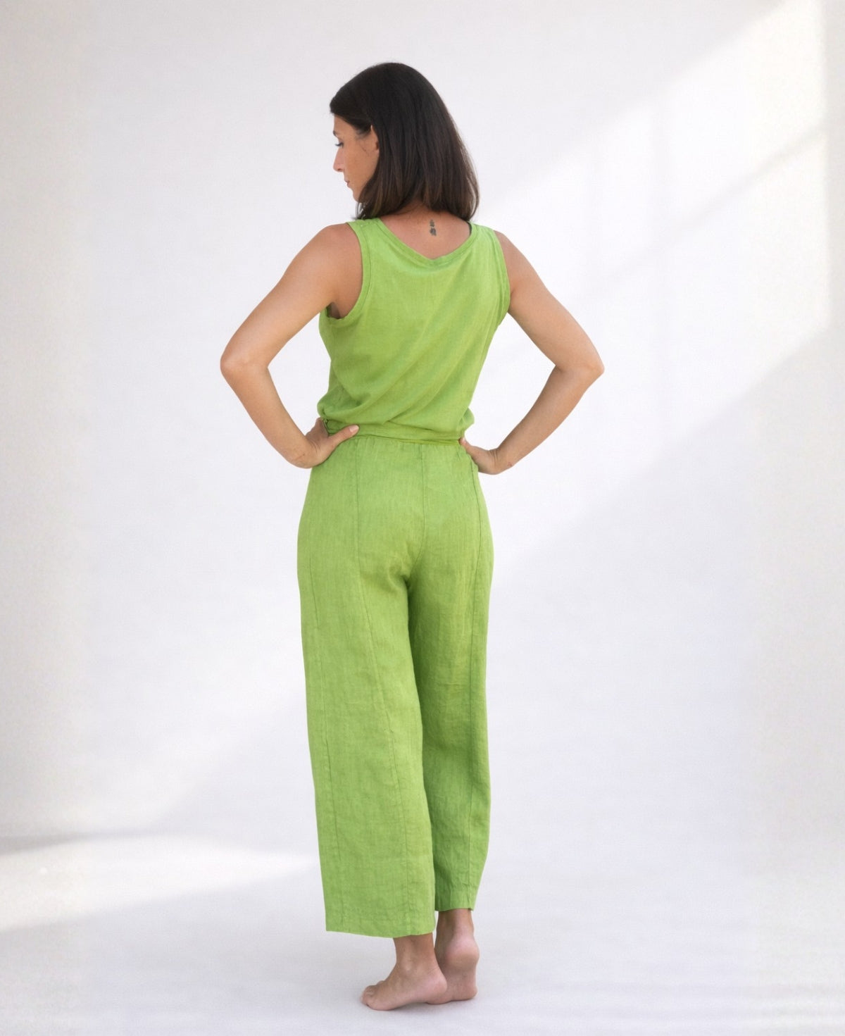 Back view of kiwi green linen palazzo pants showing stretch waistband, clean seams, and natural linen finish.