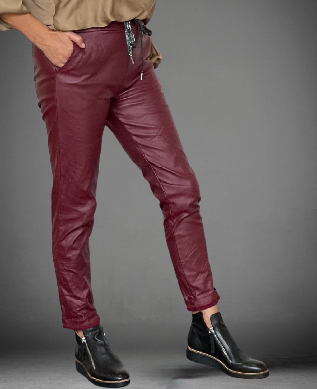 Close-up side view of the wine vegan leather pants, highlighting the smooth, luxe texture.