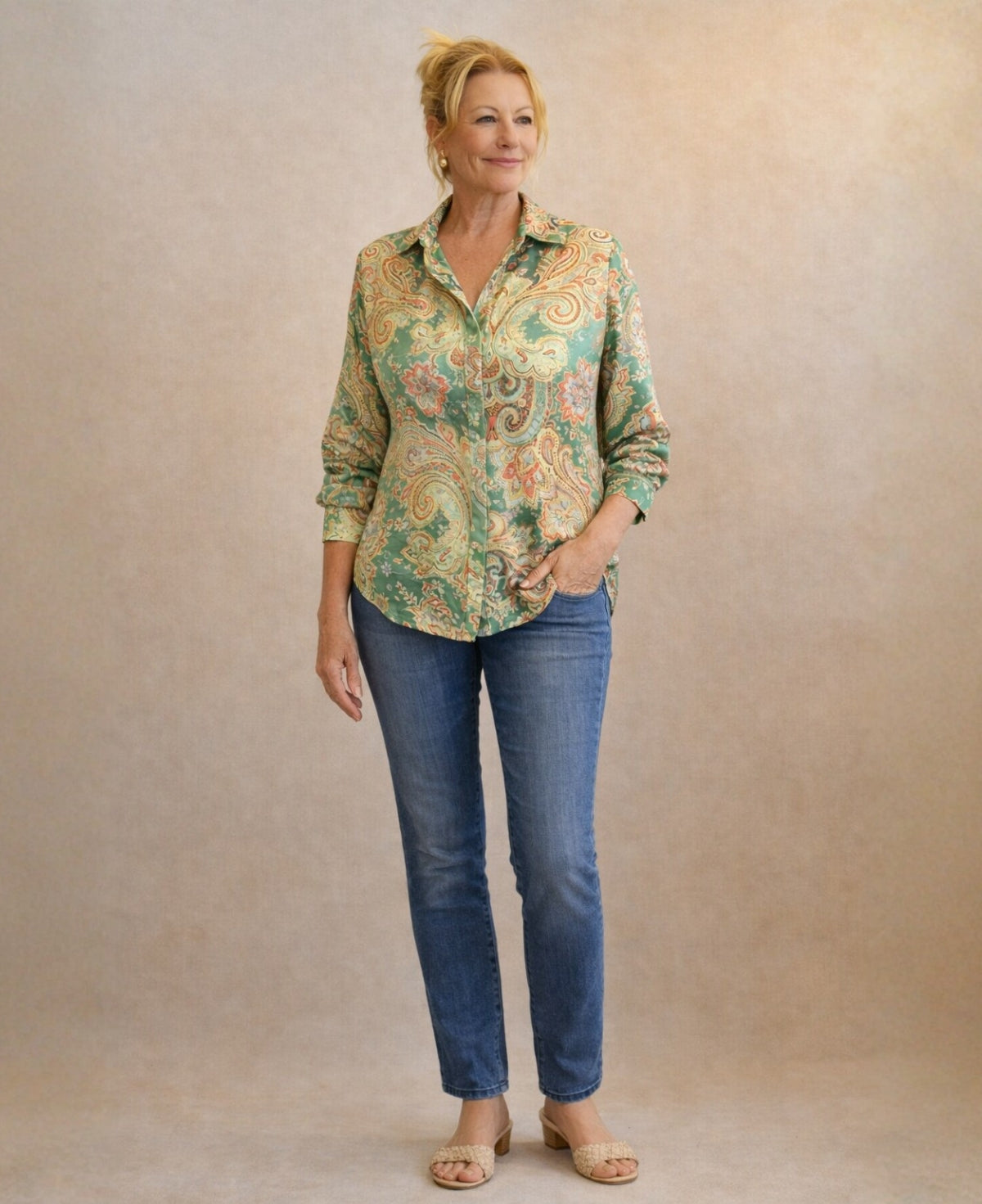 Full body view of Lotus Silk Shirt in green paisley with denim jeans showing relaxed drape and curved hem