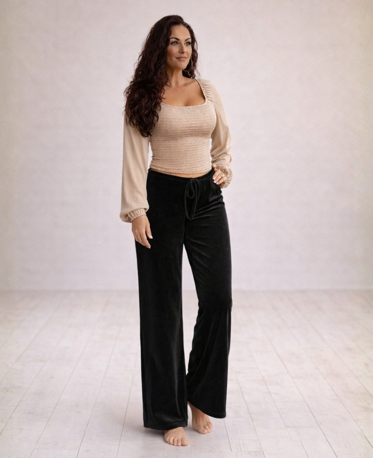 Model wearing black Marshmallow Lounge Pants in soft velour fabric, featuring a relaxed wide-leg fit and adjustable drawstring waist, photographed in warm minimalist studio lighting.