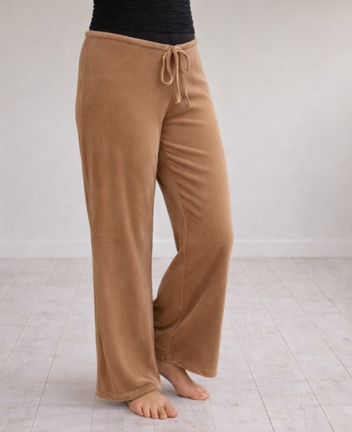 Close-up of camel Marshmallow Lounge Pants highlighting the plush velour texture, fluid drape, and wide-leg silhouette, captured in a warm minimalist studio setting.