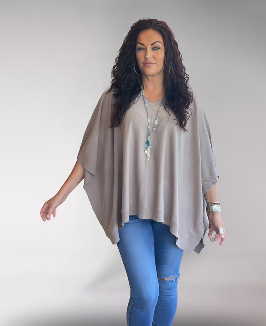Close-up of Mocha Soft Knit Poncho displaying soft knit texture, fine ribbed edging, and subtle V-neckline detail.