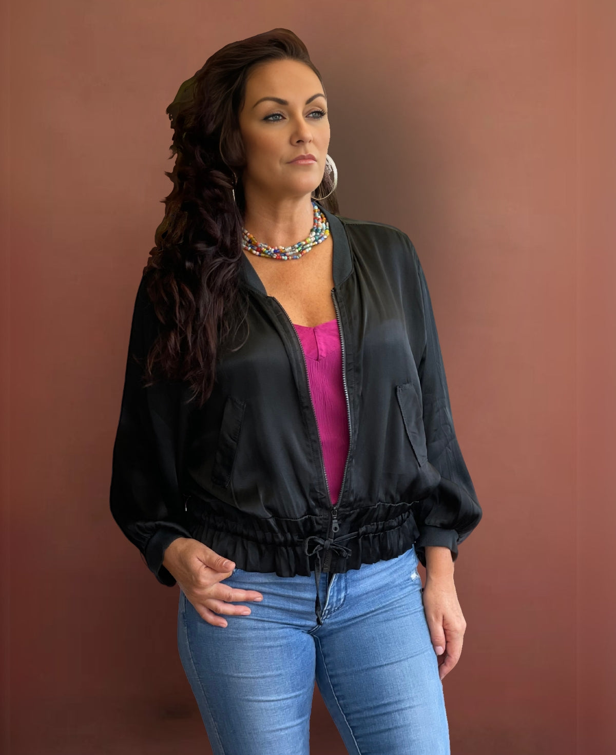 Sleek black satin bomber jacket featuring ribbed knit accents, a black gunmetal zipper, faux flap pockets, and an adjustable cinched waist for a bold yet refined look