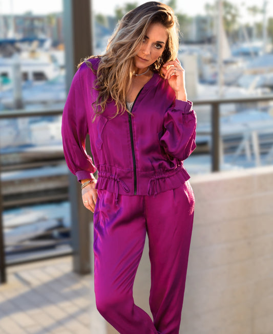 Chic sangria satin bomber jacket with ribbed cuffs, a black gunmetal zipper, faux flap pockets, and an adjustable drawstring waist for effortless sophistication.