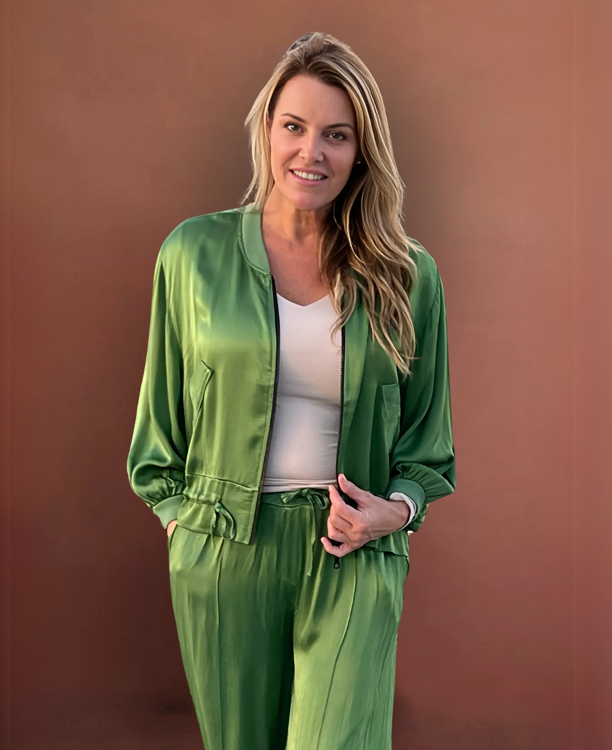 Vibrant apple green satin bomber jacket with ribbed knit details, a black gunmetal zipper, faux flap pockets, and an adjustable cinched waist for a striking, fashion-forward statement.