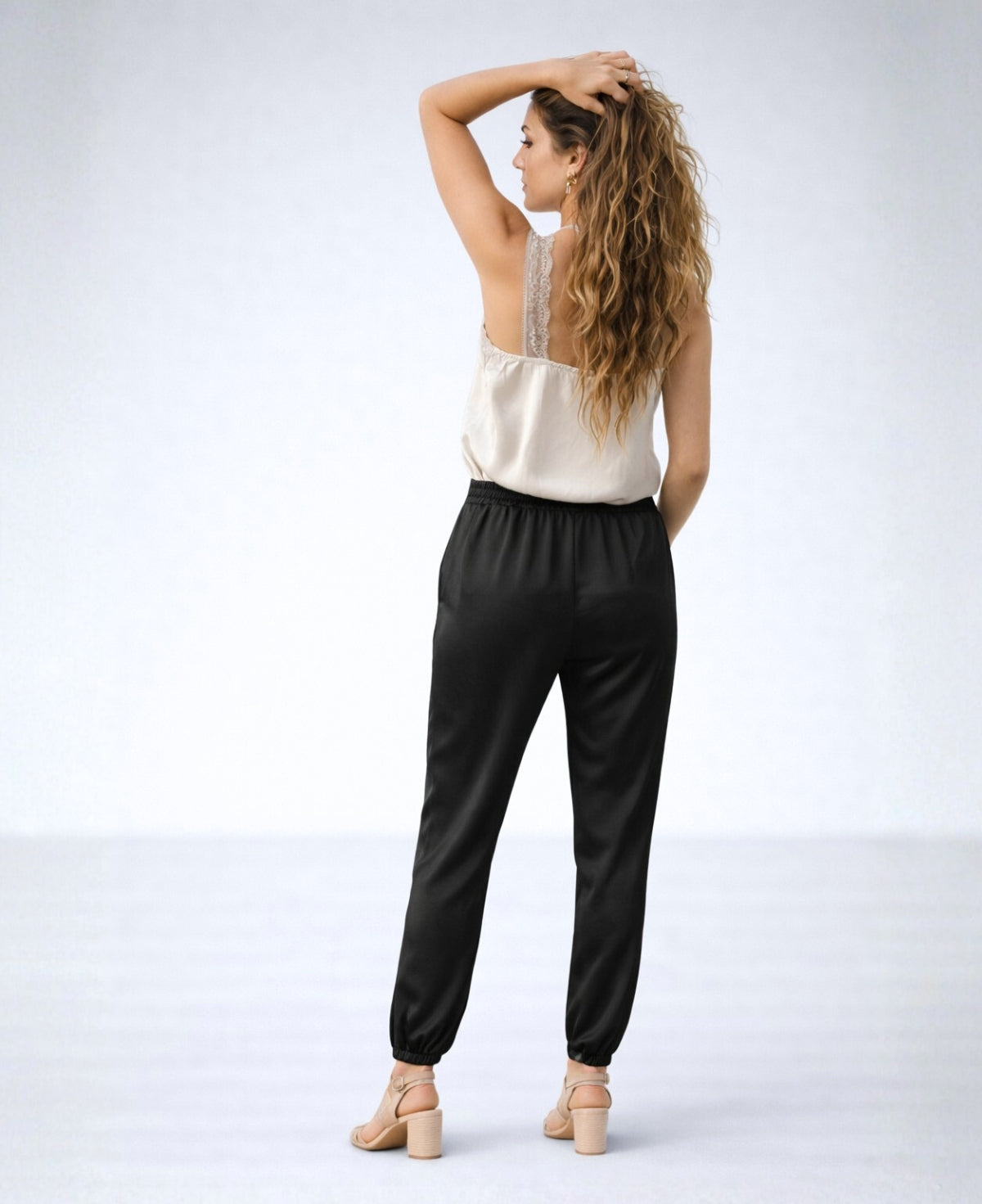 Back view of the Moulin Satin Joggers in Black, showing the elastic back waistband, relaxed satin fit, gathered ankle cuffs, and soft drape through the legs.