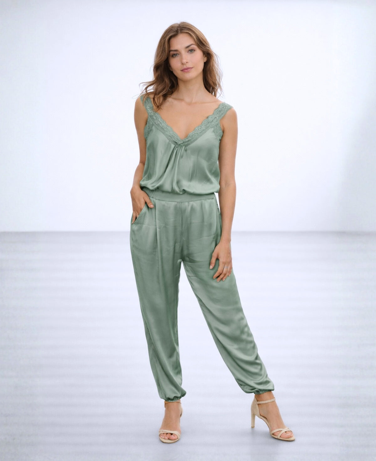 Front view of the Moulin Satin Joggers in Light Sage, styled with a satin camisole and heels, showing the soft drape, relaxed fit, and gathered ankle cuffs.