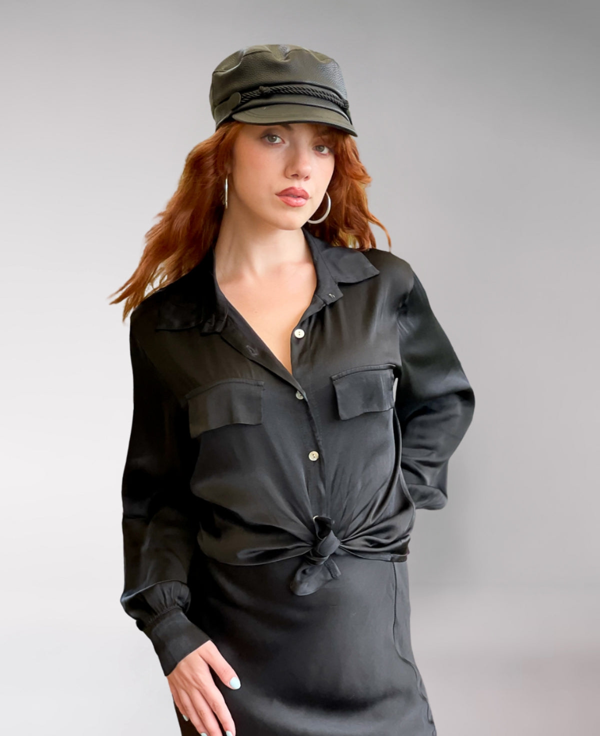 Timeless black satin button-up shirt with a structured collared neckline, front flap pockets, and buttoned cuffs. A chic and sophisticated must-have.