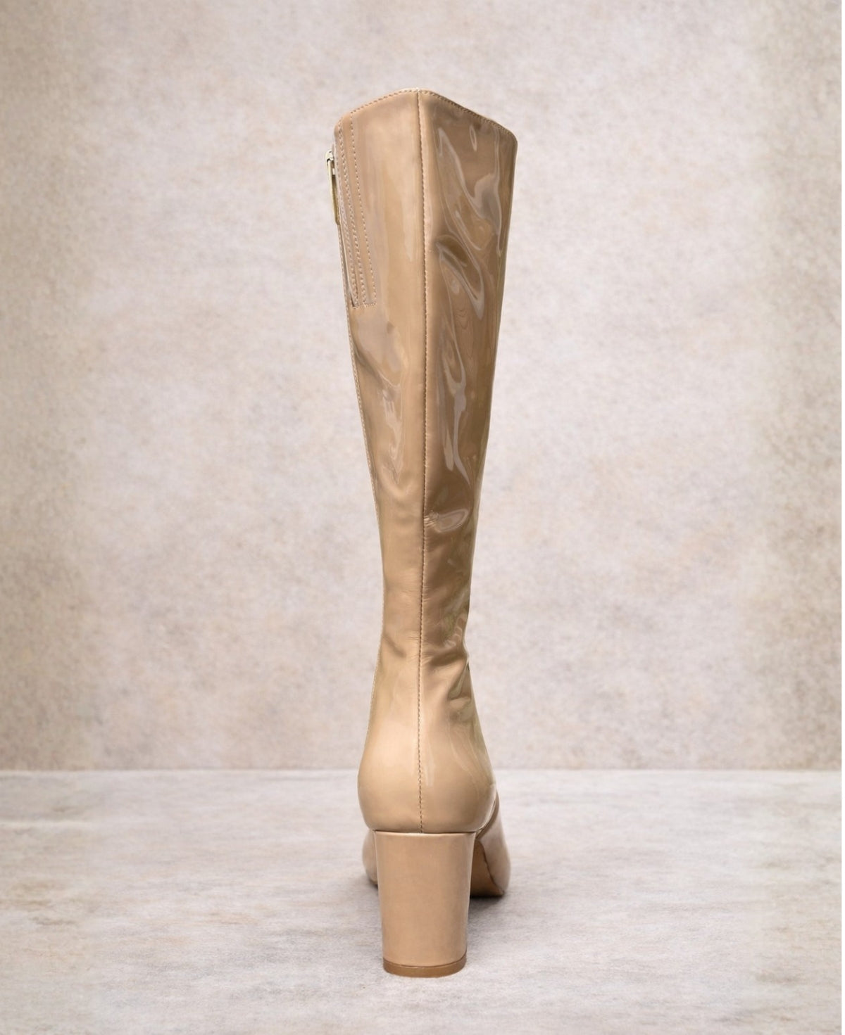 Back view of dark nude patent knee high boots highlighting the block heel and sleek fitted shaft