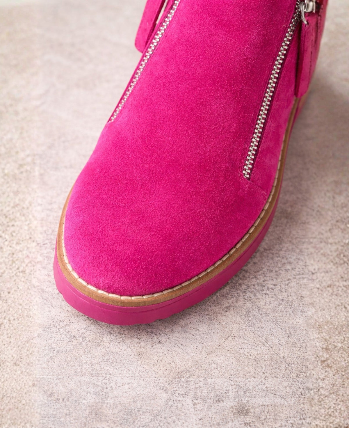 Close-up of the rounded toe and suede texture of the Opal fuchsia ankle boots with contrast stitching and rubber sole.