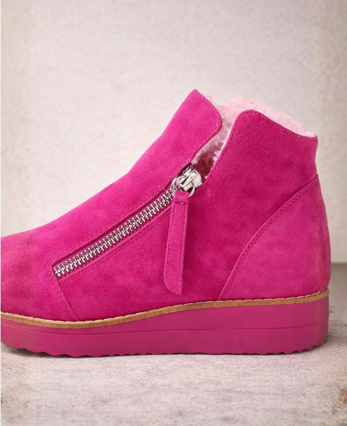 Detailed view of the twin silver zip, suede pull tab and soft faux fur lining on the Opal fuchsia ankle boots.