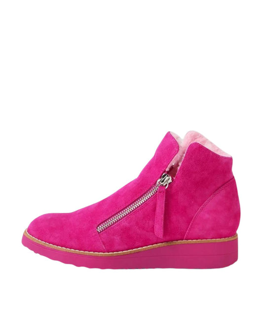 Vibrant fuchsia suede ankle boots with twin-zip closure and faux fur lining, side profile showcasing wedge sole and high-top design.
